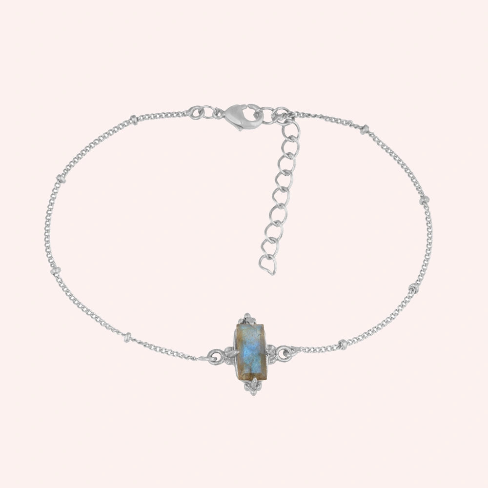 Stone_bracelet_in_sterling_silver_with_a_baguette_labradorite_at_front_angle_view_on_solid_pink_background