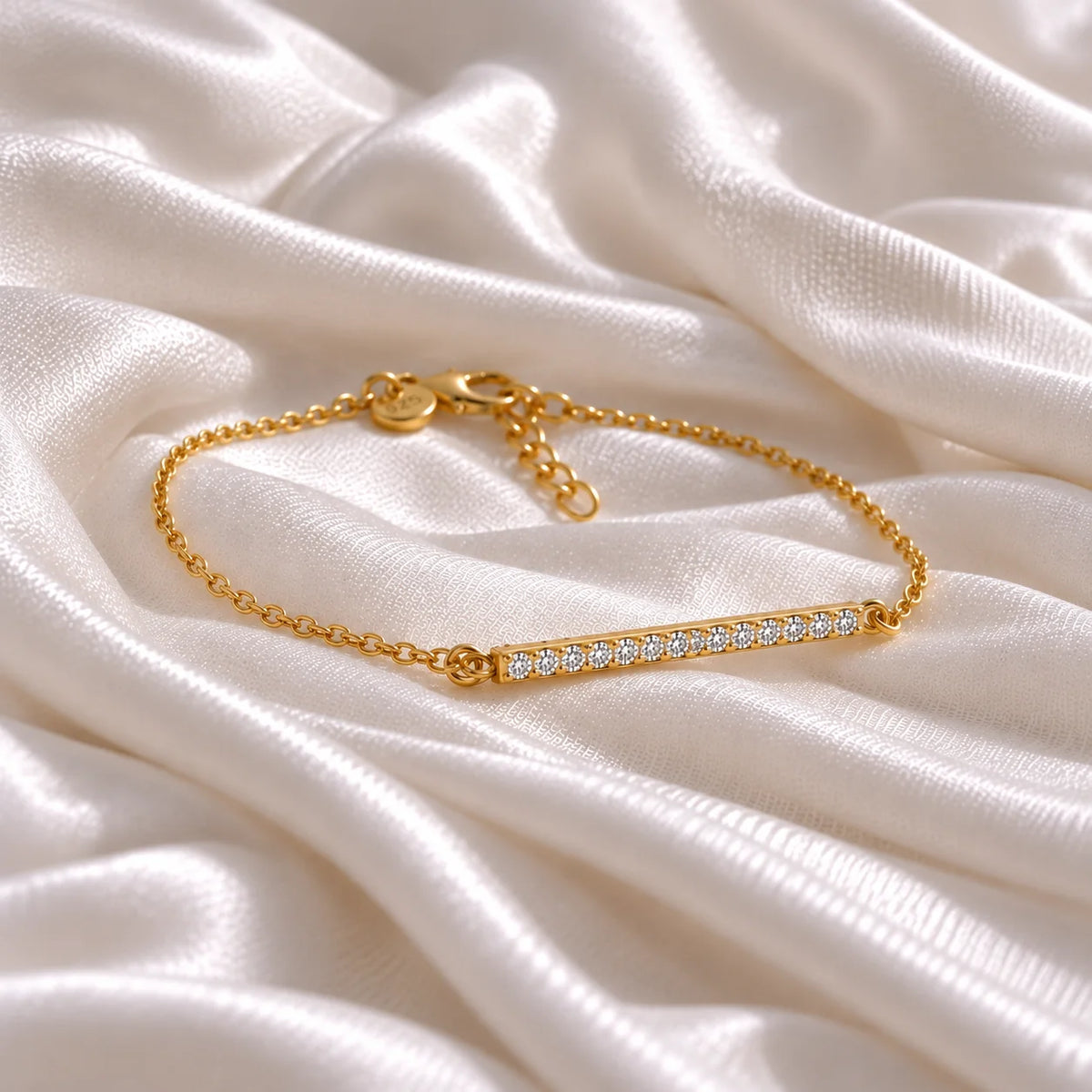 Stone_bracelet_in_gold_plated_silver_in_a_bar_design_with_CZ_stones_at_side_angle_view_on_soft_fabric_background
