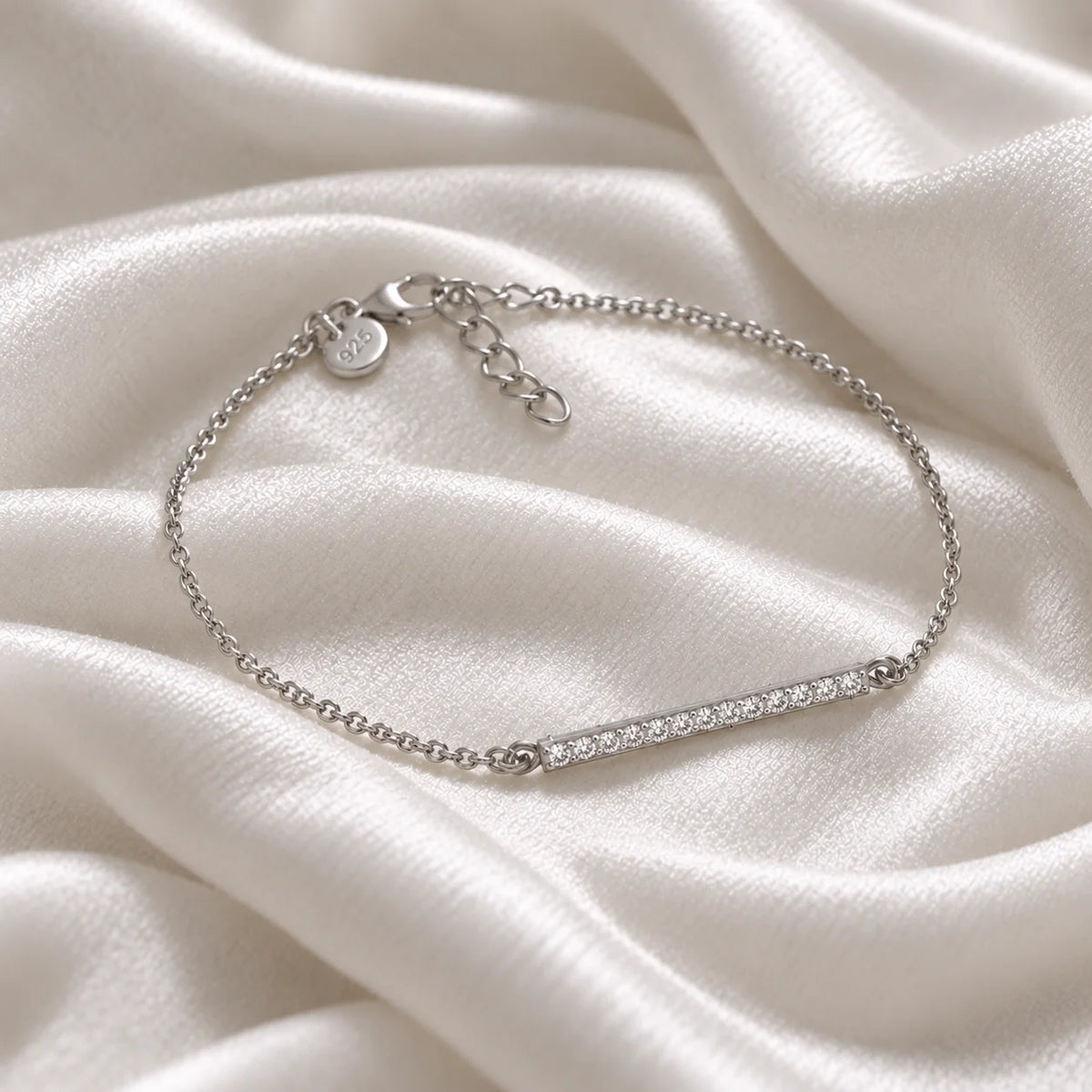 Stone_bracelet_in_sterling_silver_in_a_bar_design_with_CZ_stones_at_side_angle_view_on_soft_fabric_background