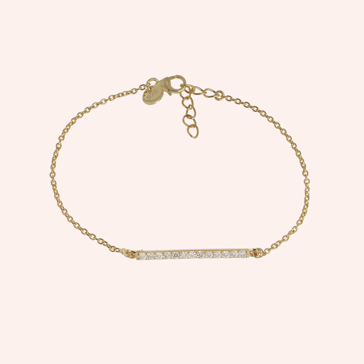 Stone_bracelet_in_gold_plated_silver_in_a_bar_design_with_CZ_stones_at_front_angle_view_on_solid_pink_background