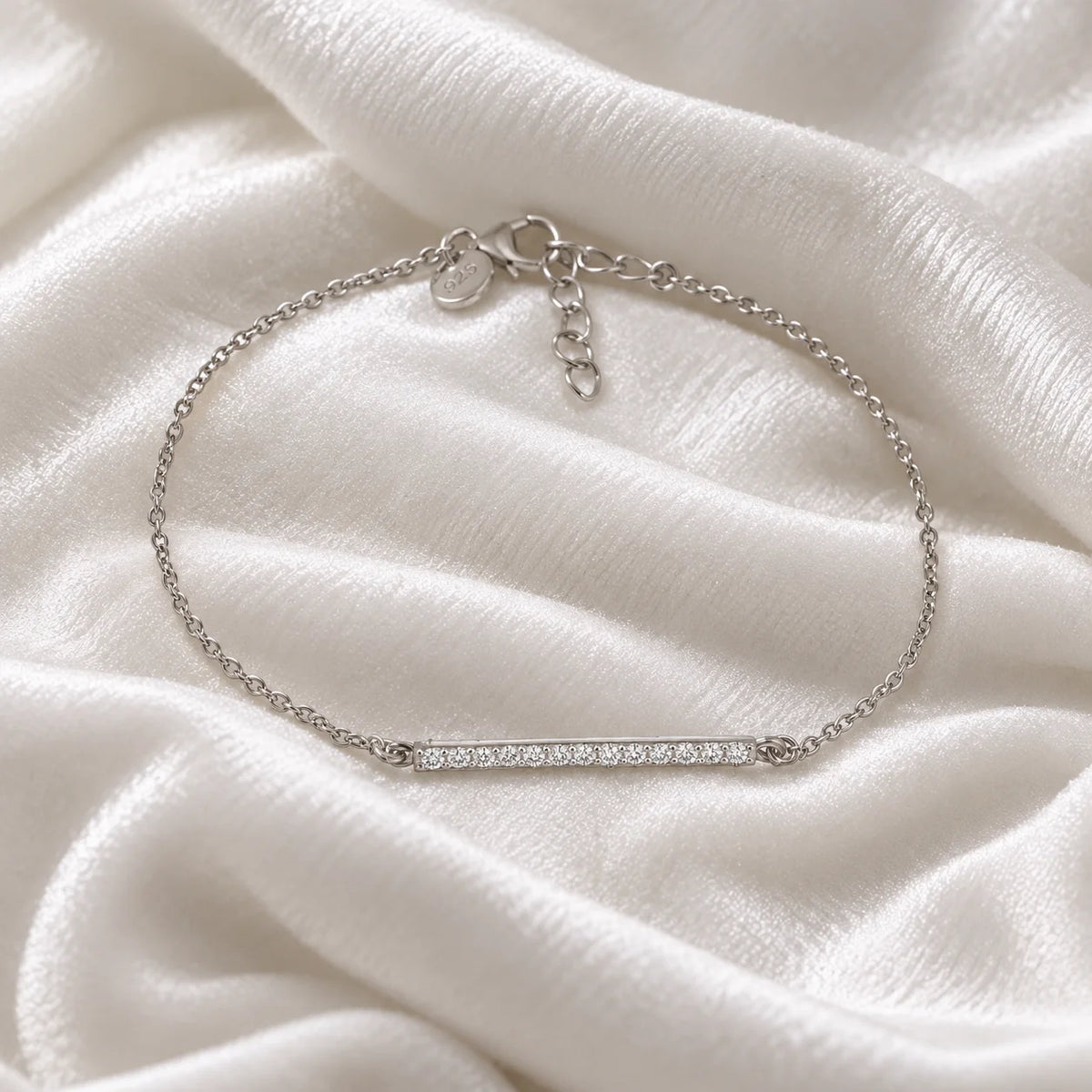 Stone_bracelet_in_sterling_silver_in_a_bar_design_with_CZ_stones_at_front_angle_view_on_soft_fabric_background
