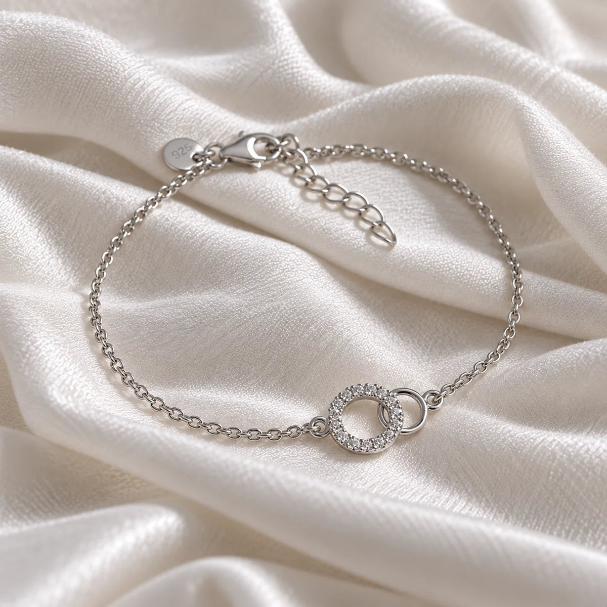 Stone_bracelet_in_sterling_silver_in_an_interlocking_design_at_side_angle_view_on_soft_fabric_background