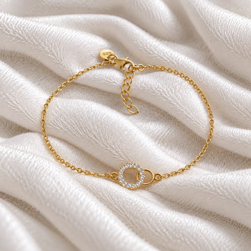 Stone_bracelet_in_gold_plated_silver_in_an_interlocking_design_at_front_angle_view_on_soft_fabric_background
