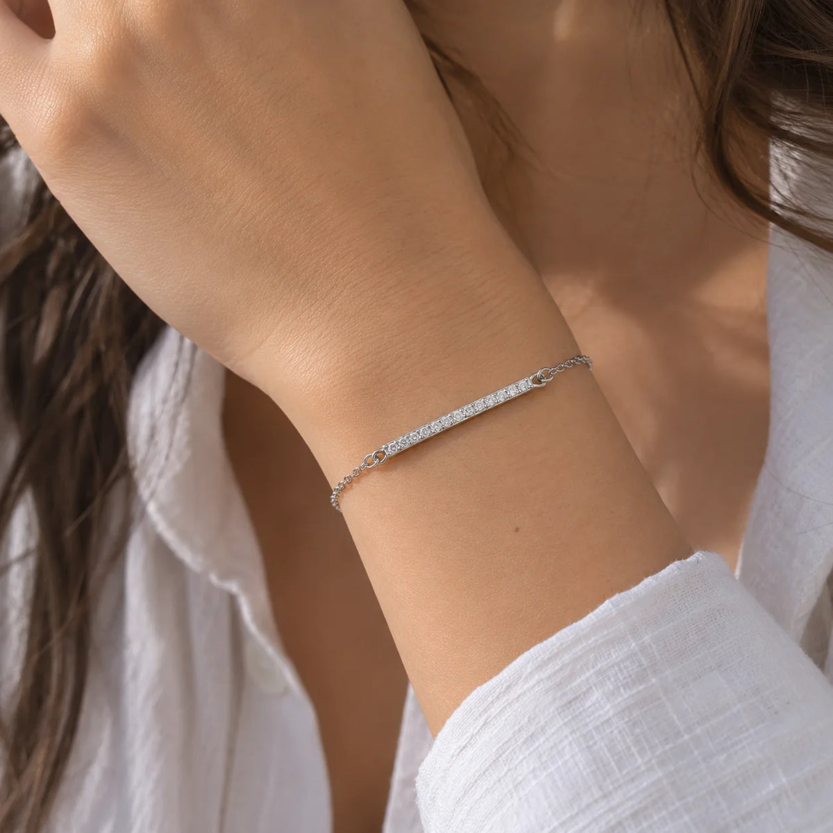 Stone_bracelet_in_sterling_silver_in_a_bar_design_with_CZ_stones_at_front_angle_view_worn_by_a_model