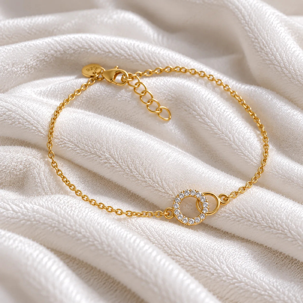 Stone_bracelet_in_gold_plated_silver_in_an_interlocking_design_at_side_angle_view_on_soft_fabric_background