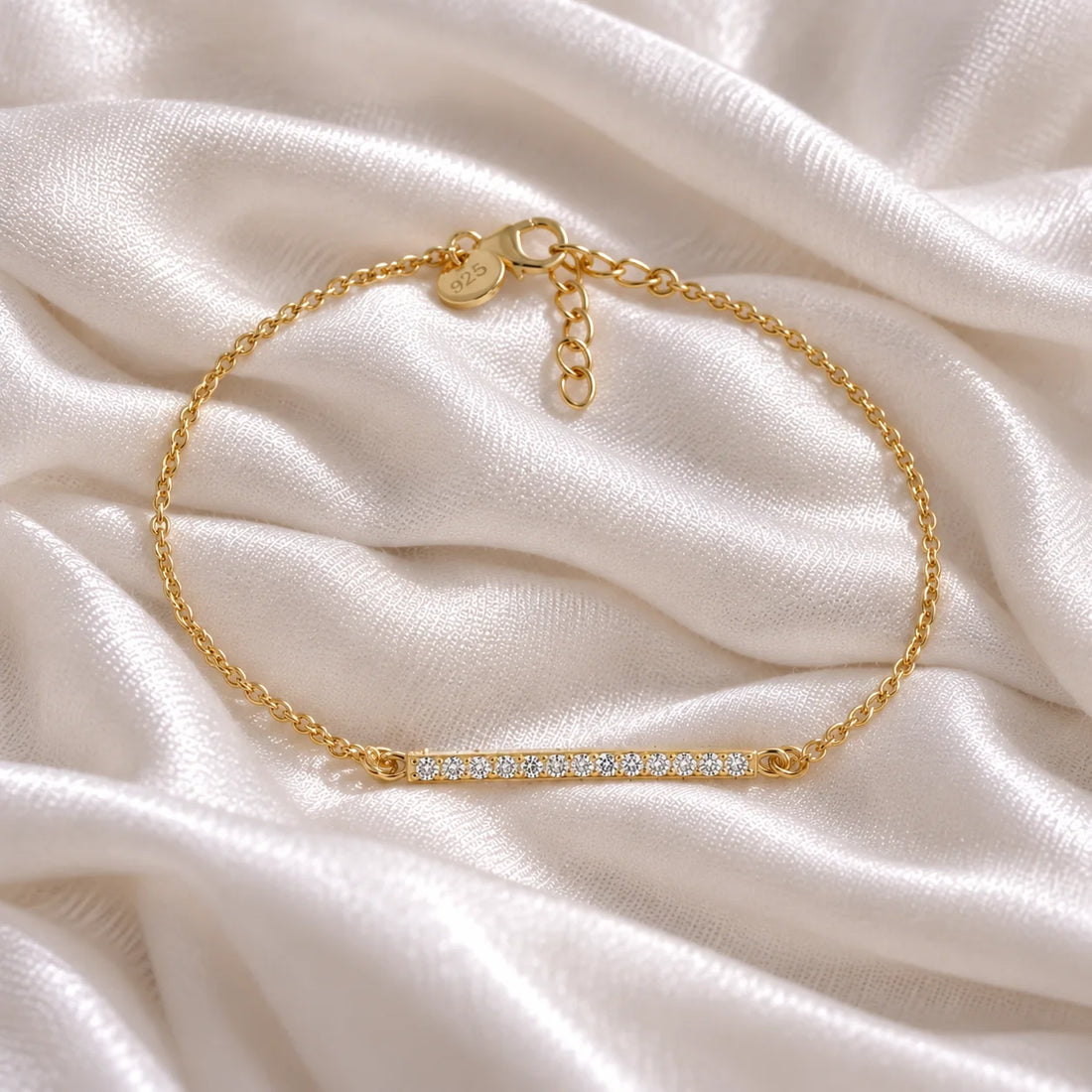 Stone_bracelet_in_gold_plated_silver_in_a_bar_design_with_CZ_stones_at_front_angle_view_on_soft_fabric_background