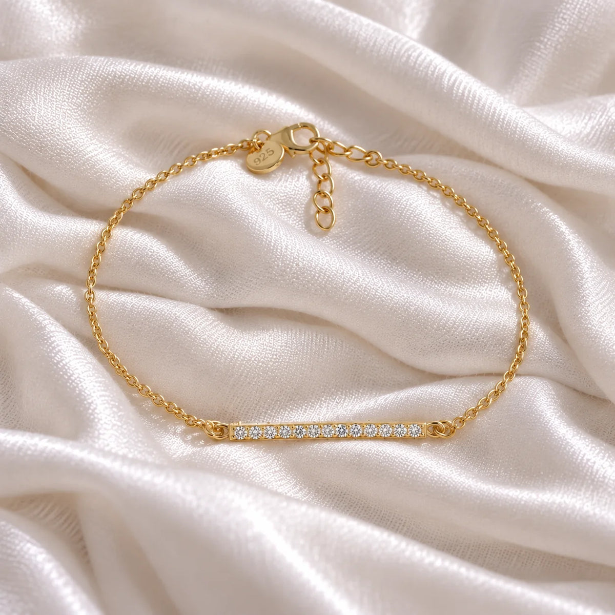 Stone_bracelet_in_gold_plated_silver_in_a_bar_design_with_CZ_stones_at_front_angle_view_on_soft_fabric_background