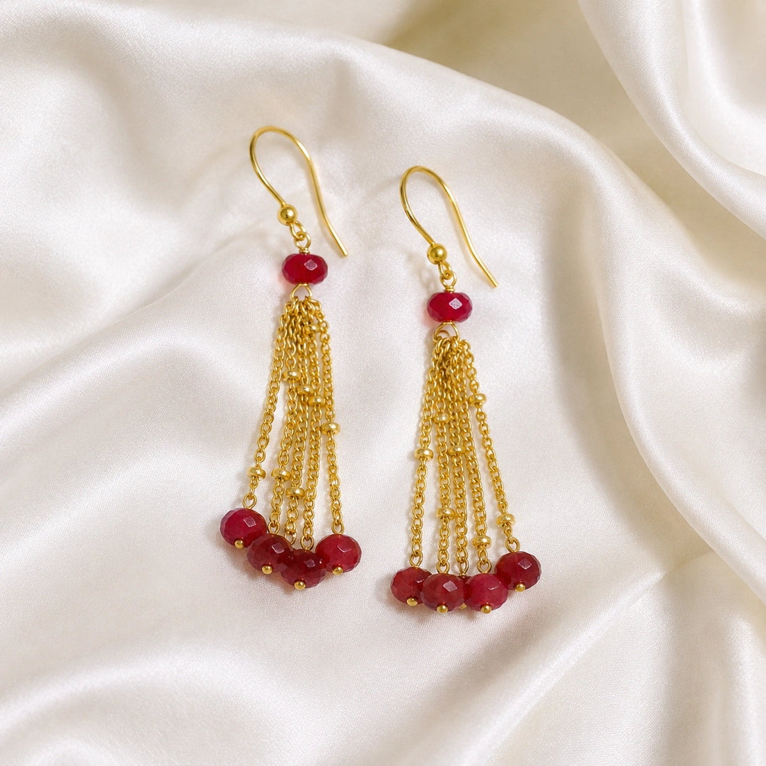 Tassel_earrings_in_gold_plated_silver_with_chain_and_ruby_stones_at_slight_angle_view_on_soft_fabric_background
