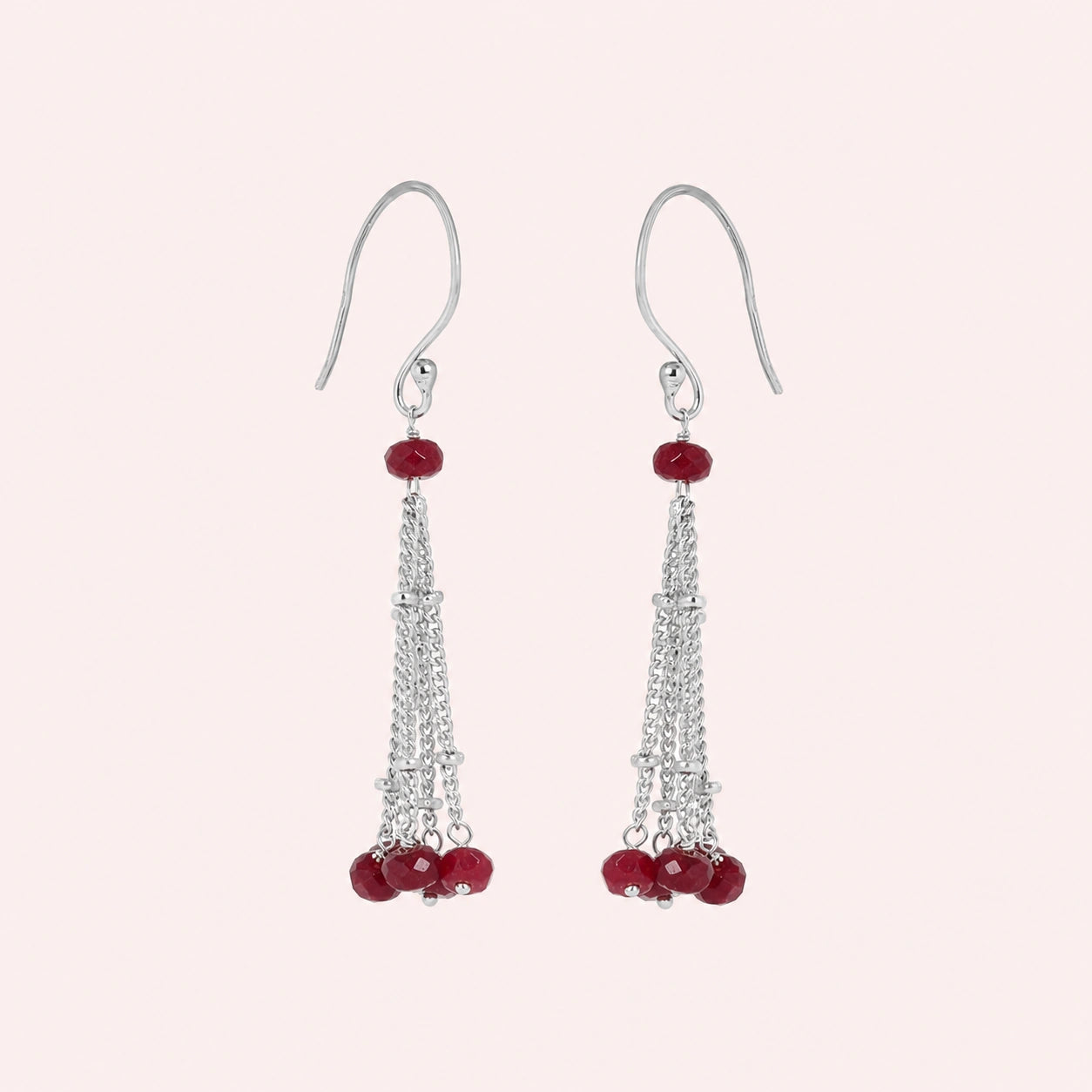 Tassel_earrings_in_sterling_silver_with_chain_and_ruby_stones_at_slight_angle_view_on_solid_pink_background