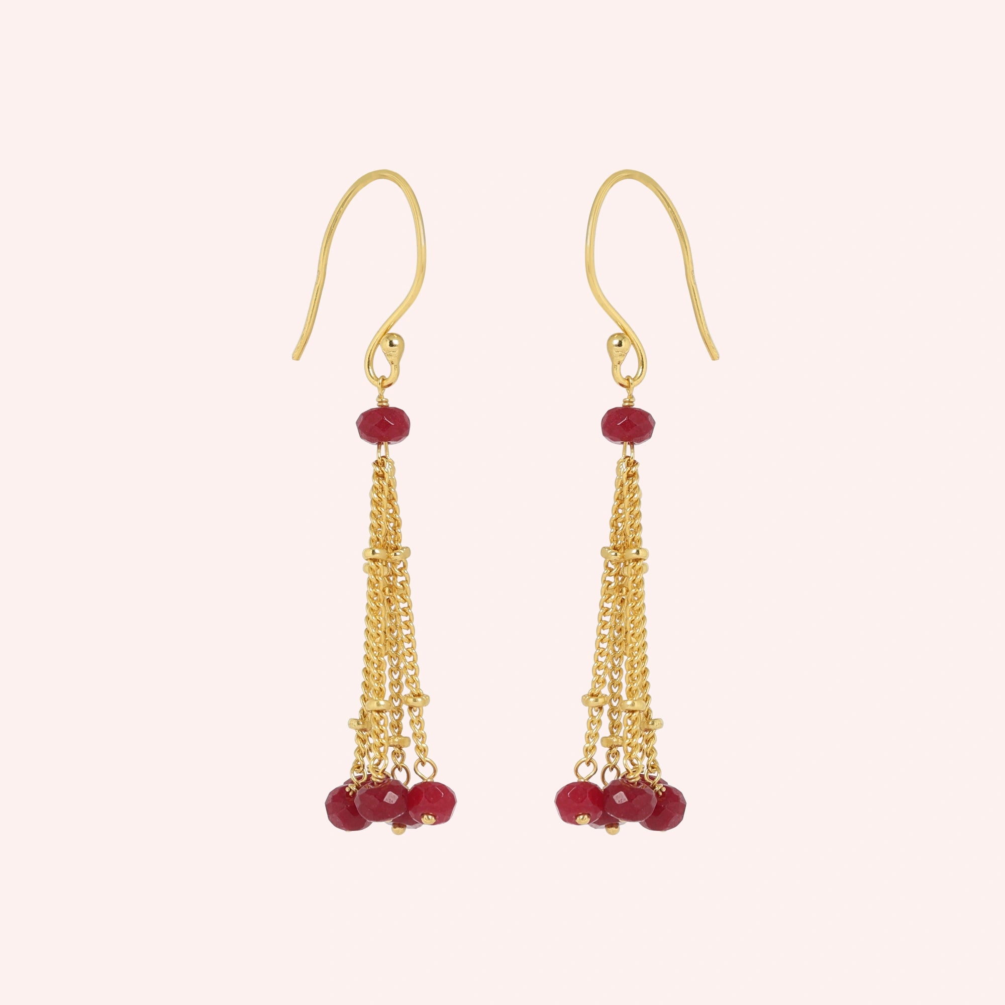 Tassel_earrings_in_gold_plated_silver_with_chain_and_ruby_stones_at_slight_angle_view_on_solid_pink_background