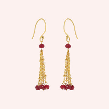 Tassel_earrings_in_gold_plated_silver_with_chain_and_ruby_stones_at_slight_angle_view_on_solid_pink_background