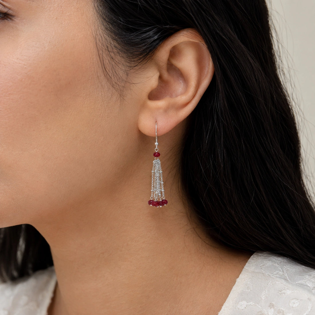 Tassel_earrings_in_gold_plated_silver_with_chain_and_ruby_stones_at_slight_angle_view_on_soft_fabric_background