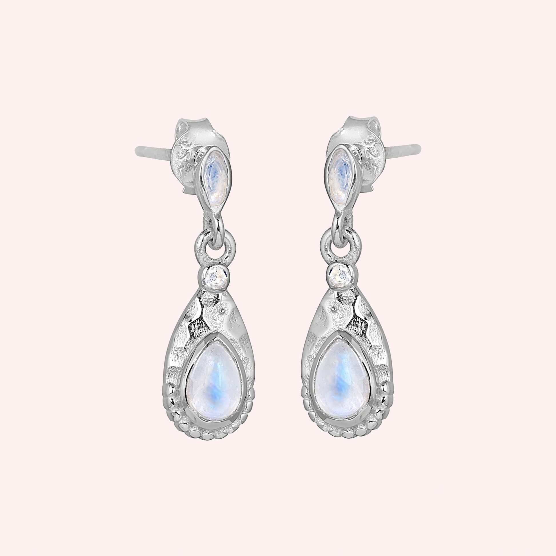 Teardrop_earrings_sterling_silver_with_moonstone_in_slightly_angled_view_on_solid_pink_background