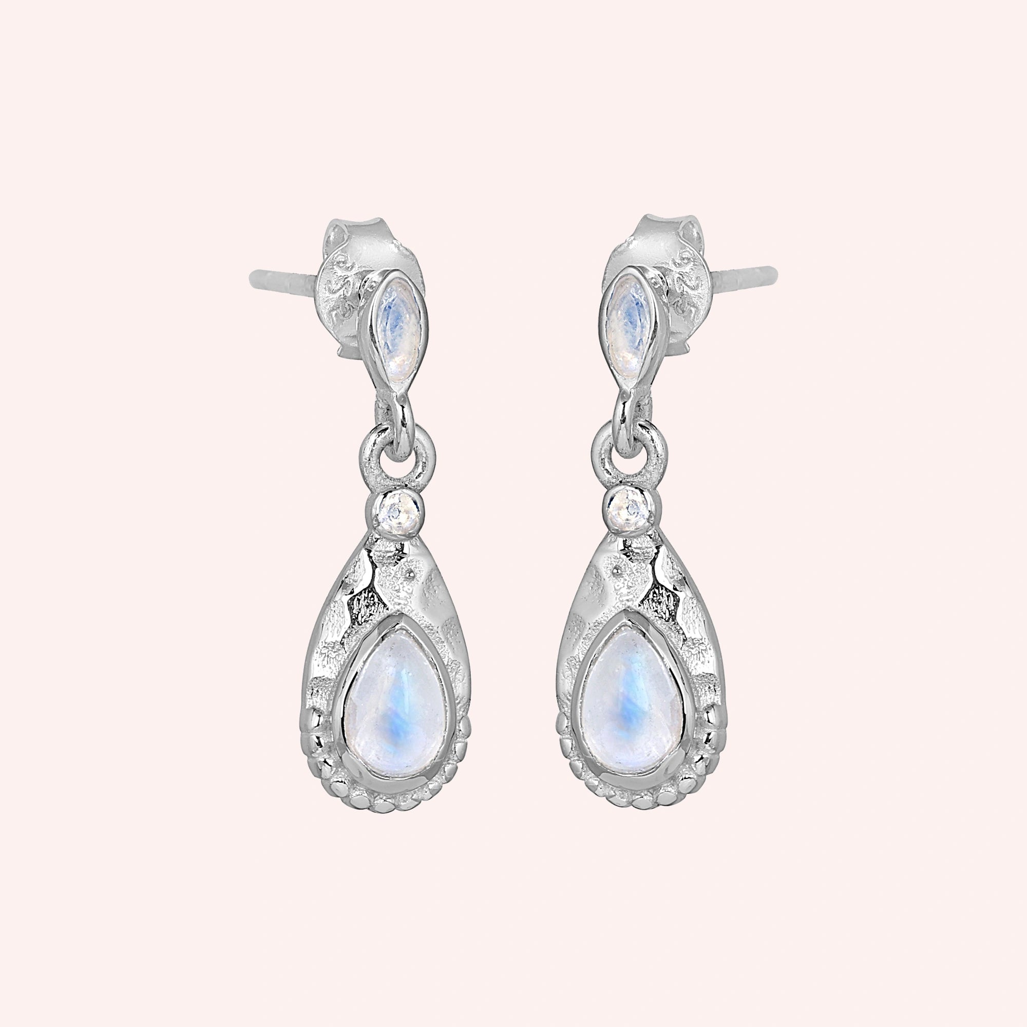 Teardrop_earrings_sterling_silver_with_moonstone_in_slightly_angled_view_on_solid_pink_background