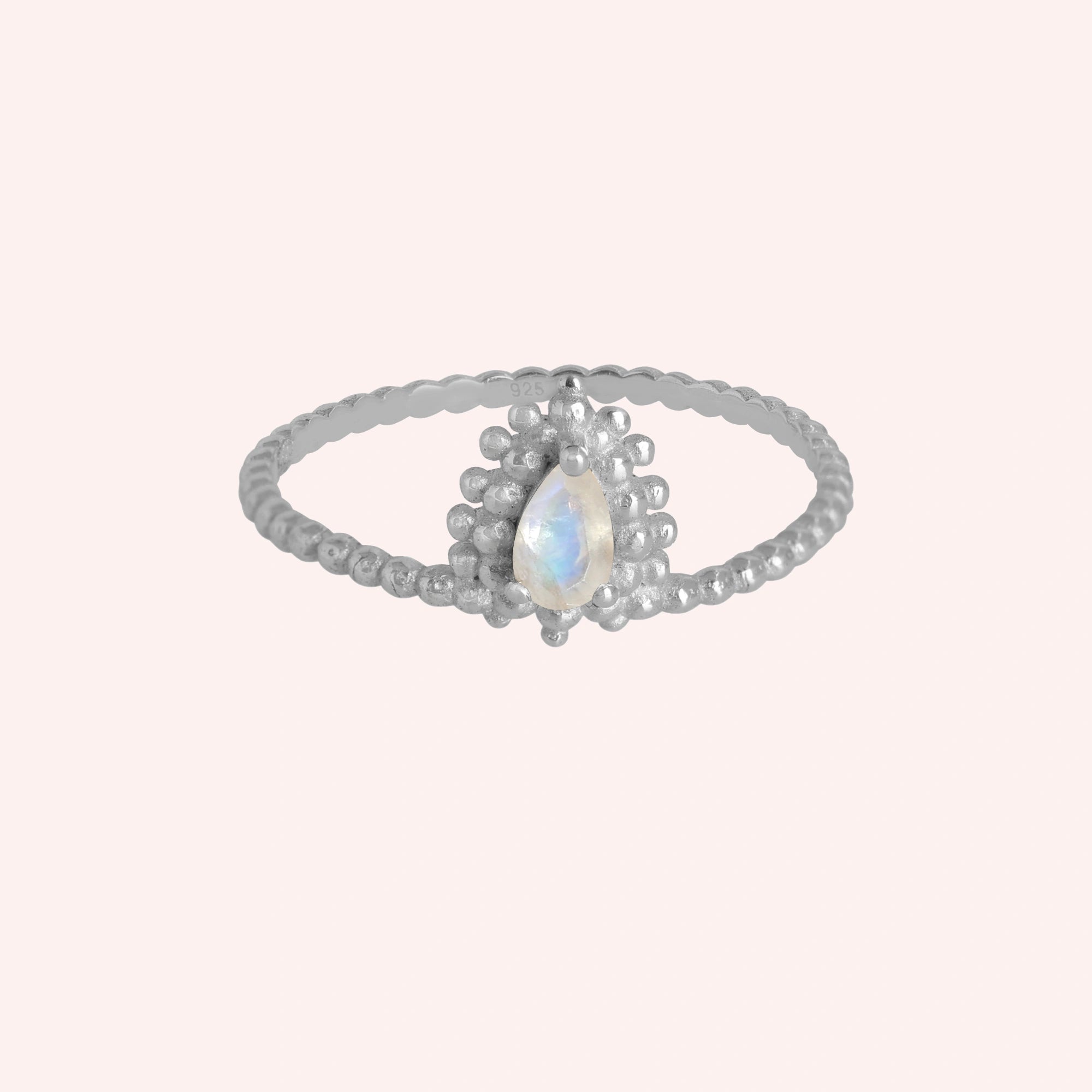 Teardrop_ring_sterling_silver_beaded_band_with_moonstone_at_front_angle_view_on_solid_pink_background