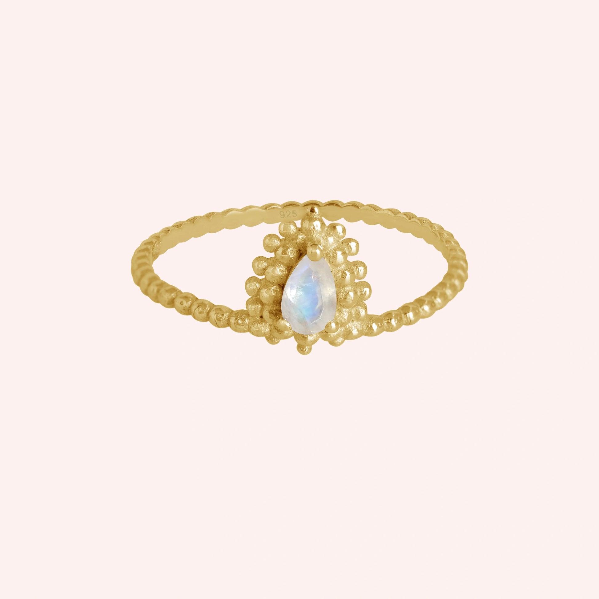 Teardrop_ring_gold_plated_silver_beaded_band_with_moonstone_at_front_angle_view_on_solid_pink_background