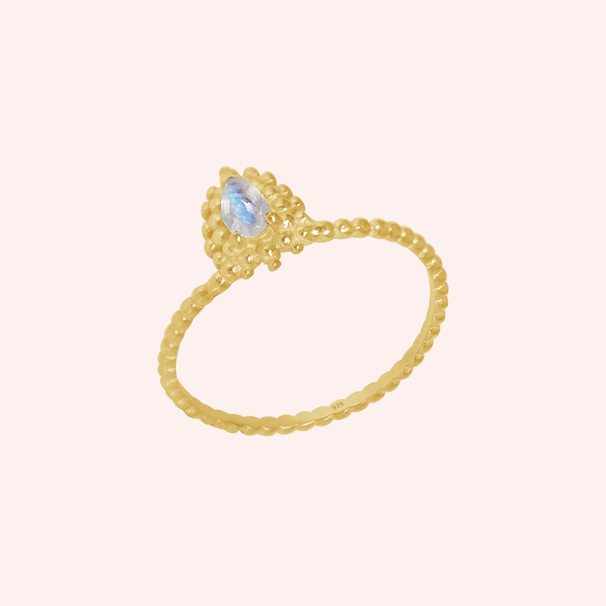 Teardrop_ring_gold_plated_silver_beaded_band_with_moonstone_at_tilted_angle_view_on_soft_fabric_background