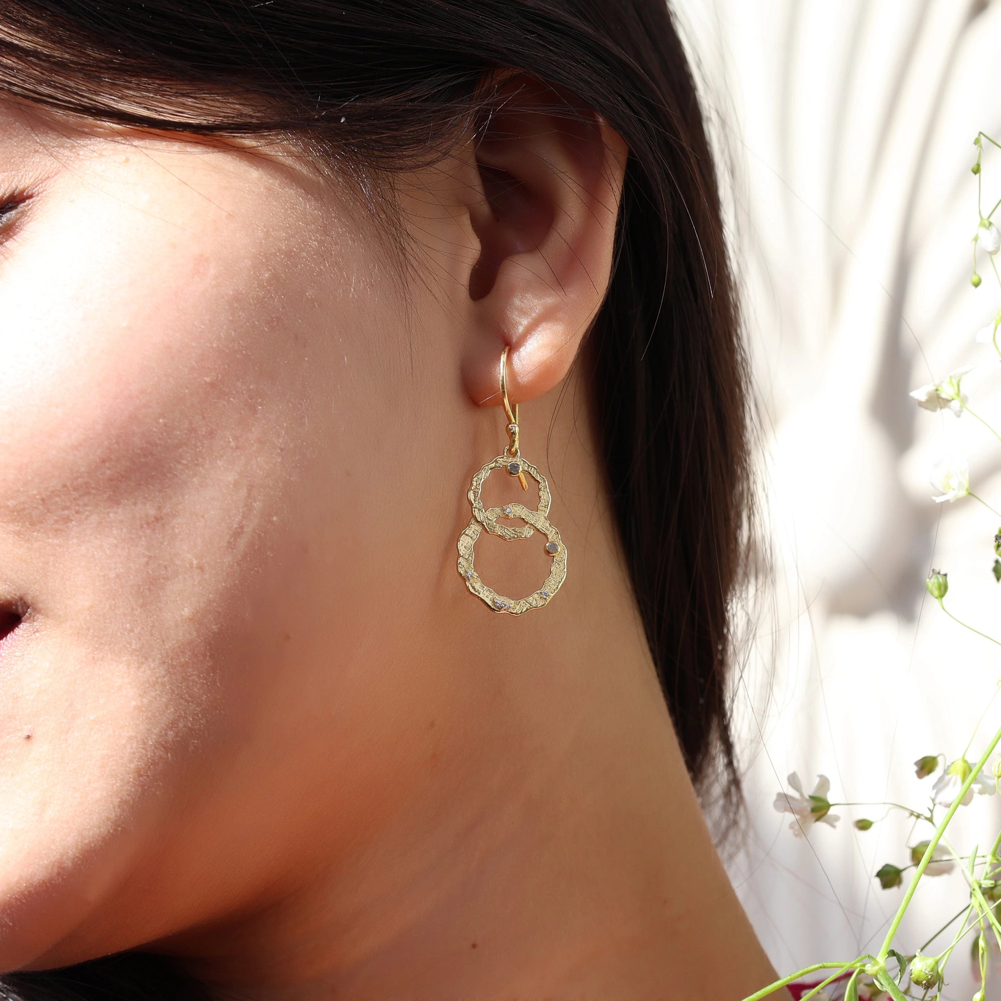 Gold plated silver dangle earrings look shown by model wearing with interlocking rings and small labradorite stones in an outdoor shot