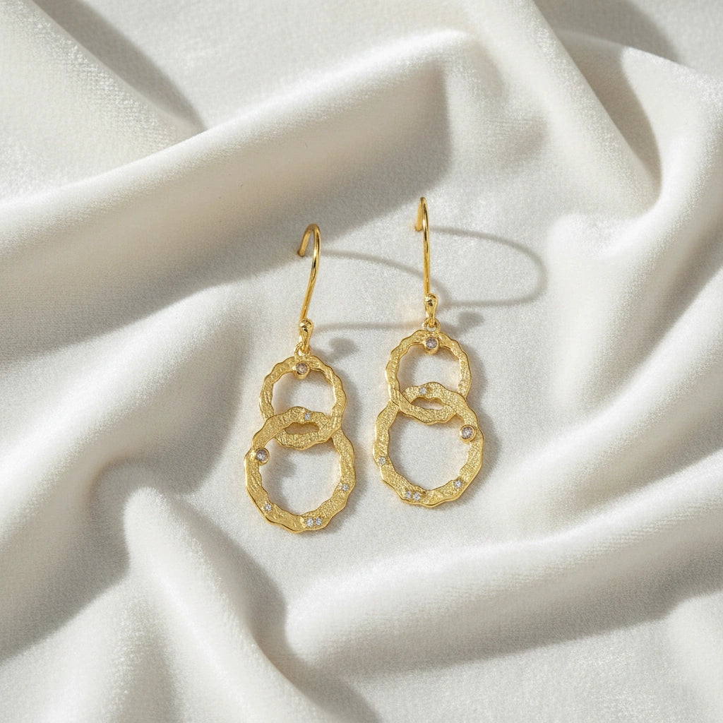 Gold-plated dangle earrings textured interlocking rings small labradorite stones slightly angled on white draped fabric