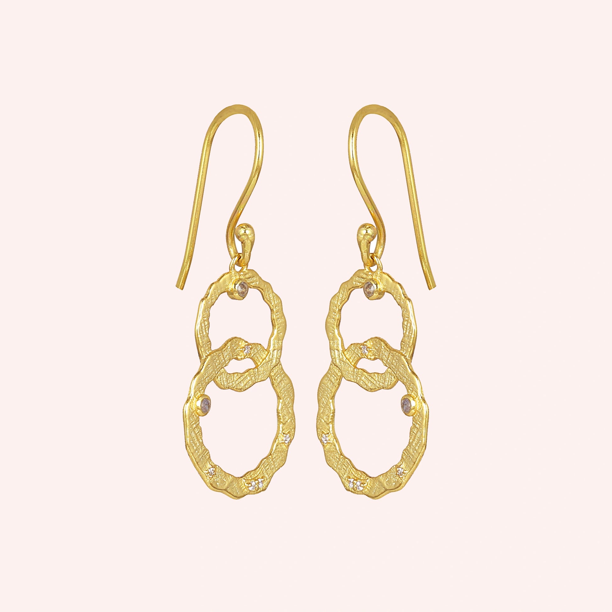 Gold-plated silver dangle earrings textured interlocking rings with small labradorite stones slightly angled on a light pink surface