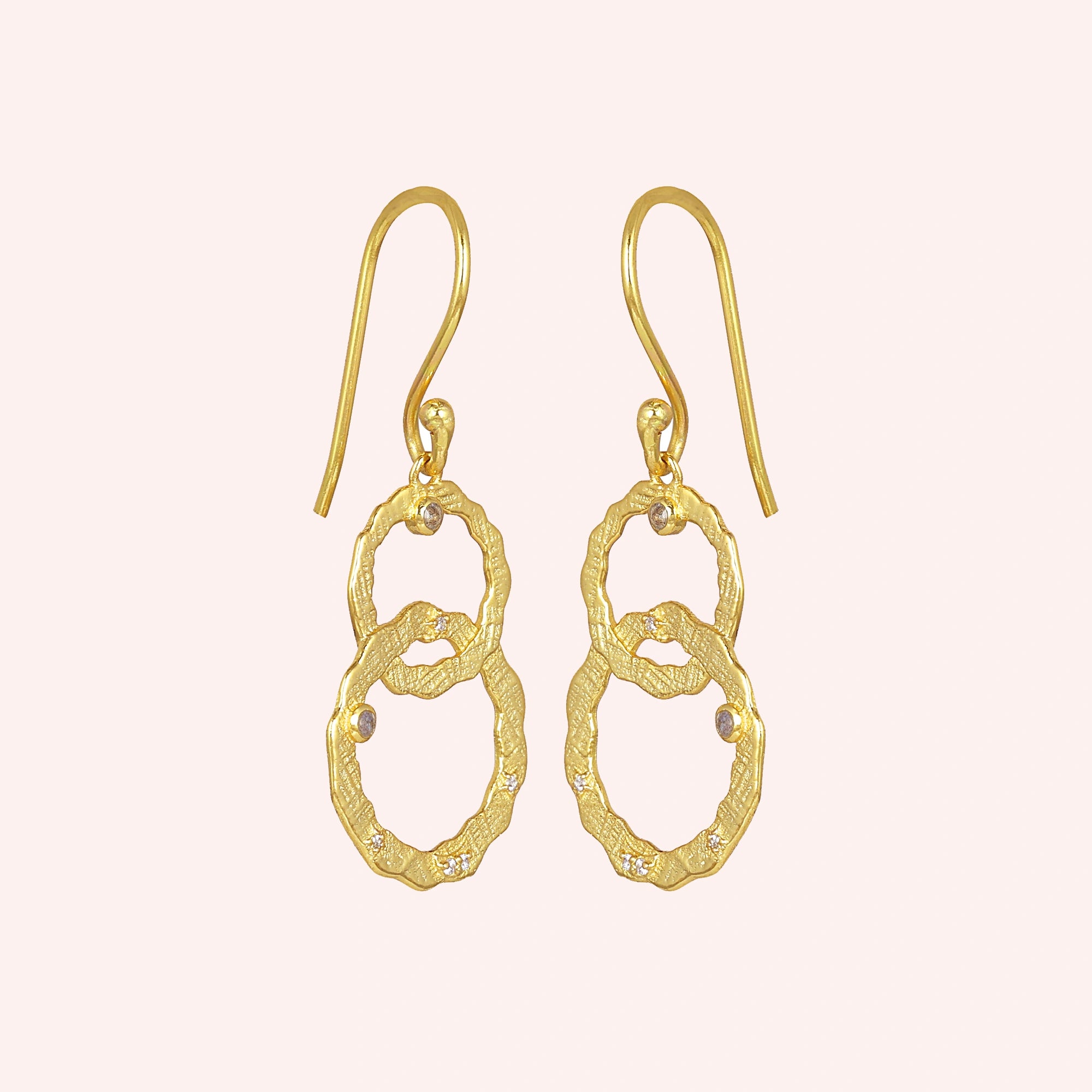 Gold-plated silver dangle earrings textured interlocking rings with small labradorite stones slightly angled on a light pink surface