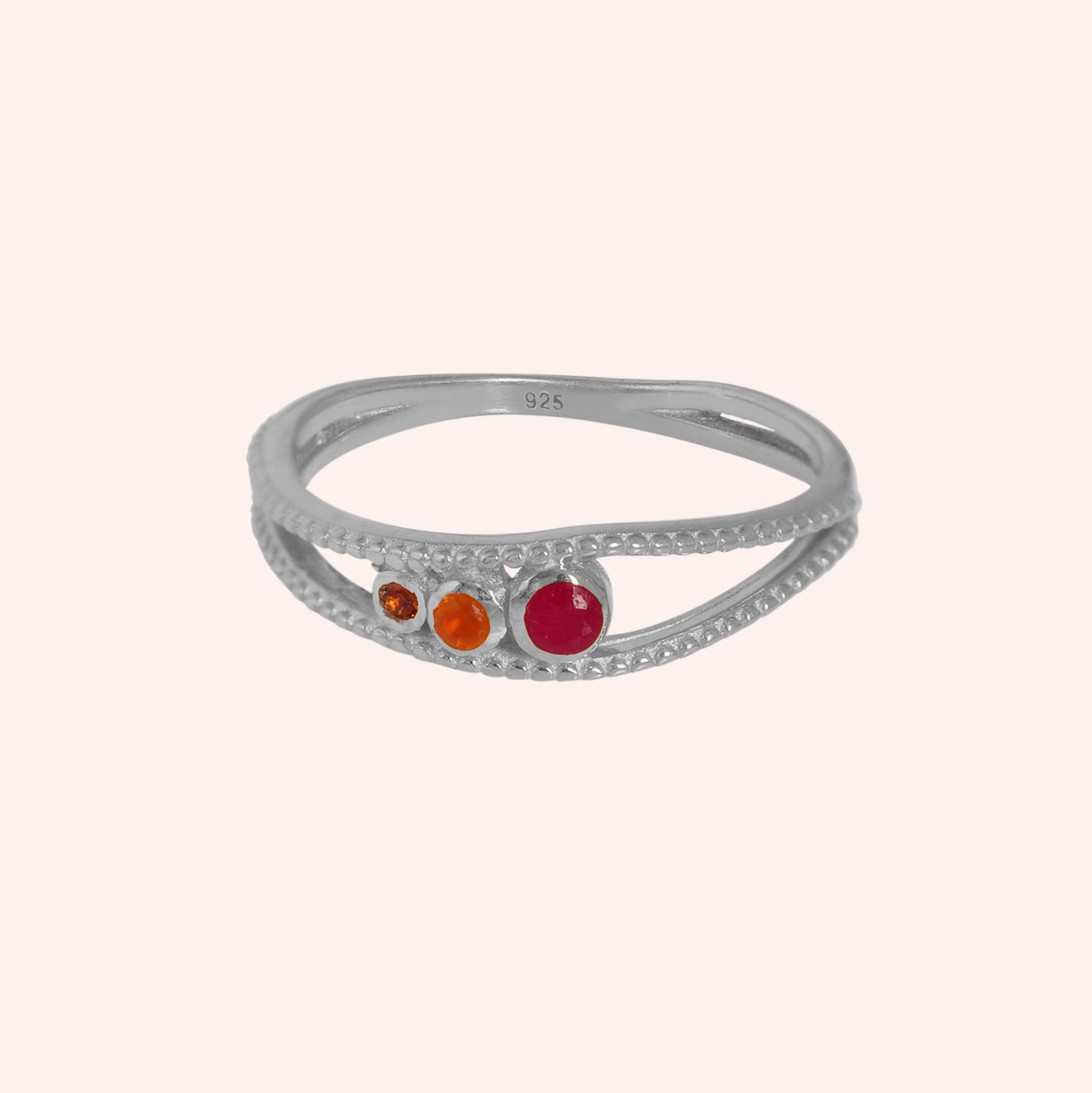 Three-stone-ring-in-sterling-silver-with-pink-red-and-orange-stones-in-front-view-on-solid-pink-background