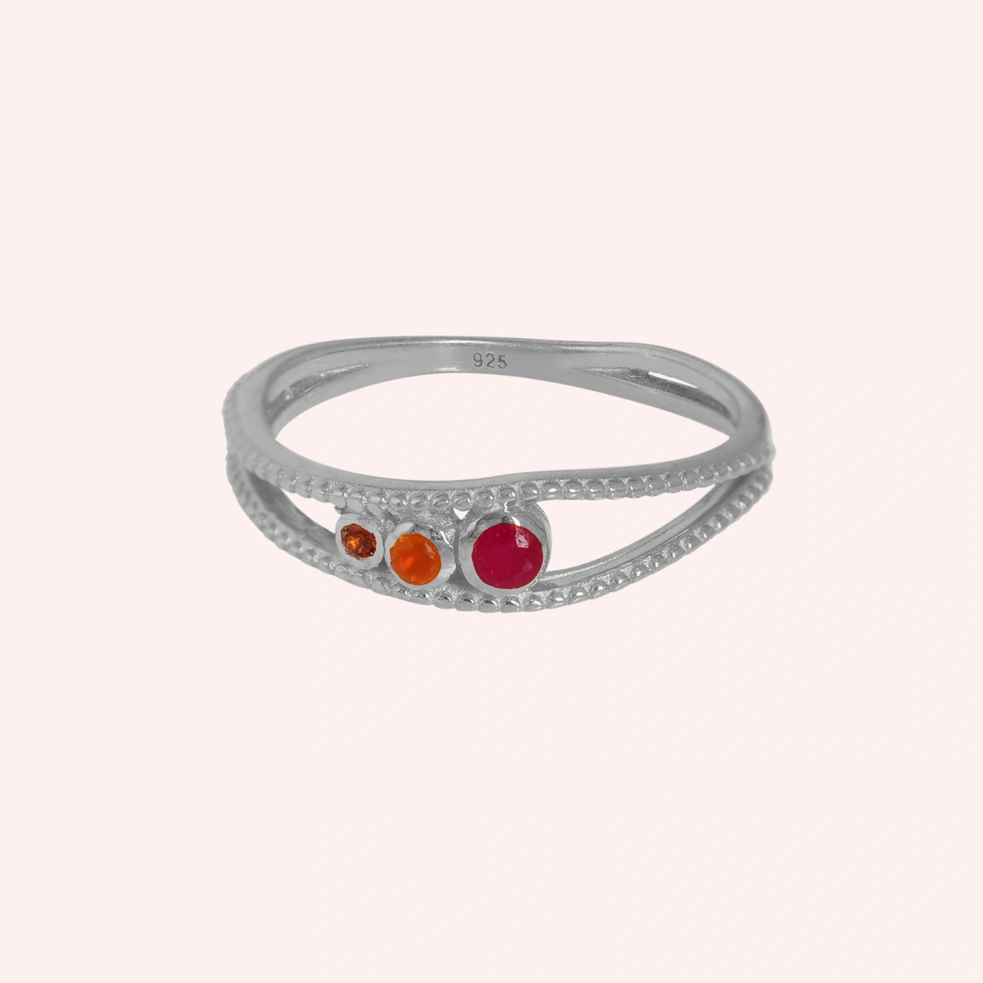 Three-stone-ring-in-sterling-silver-with-pink-red-and-orange-stones-in-front-view-on-solid-pink-background