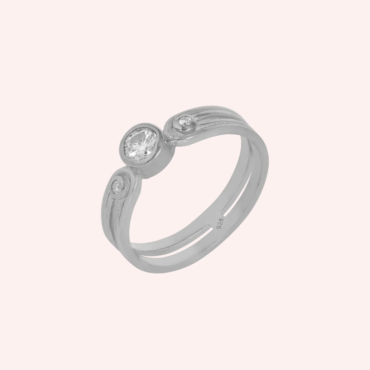 Three_stone_ring_in_sterling_silver_with_round_lab_grown_diamonds_at_side_angle_view_on_solid_pink_background