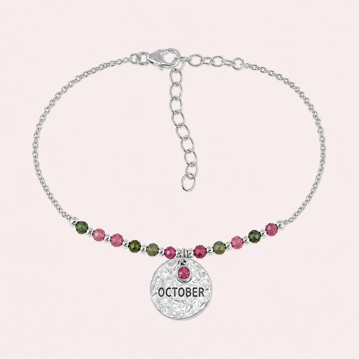 Birthstone_bracelet_in_stering_silver_with_October_charm_and_tourmaline_beads_on_fine_chain_on_solid_pink_background