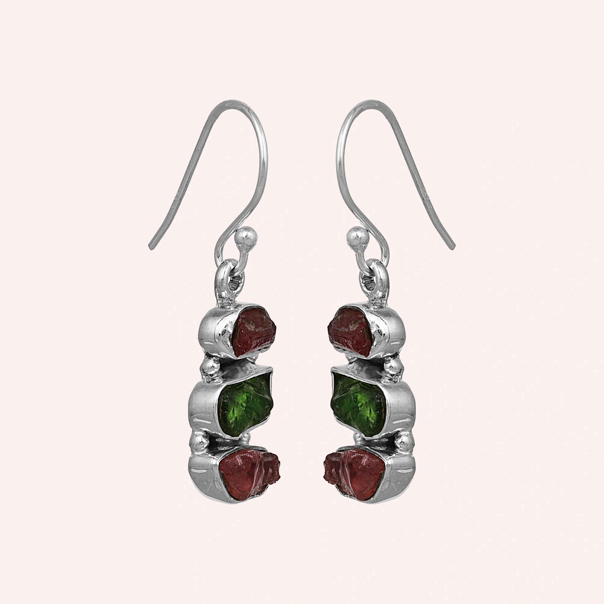 Trending_earrings_in_sterling_silver_with_three_raw_tourmaline_stones_at_slight_angle_view_on_solid_pink_background