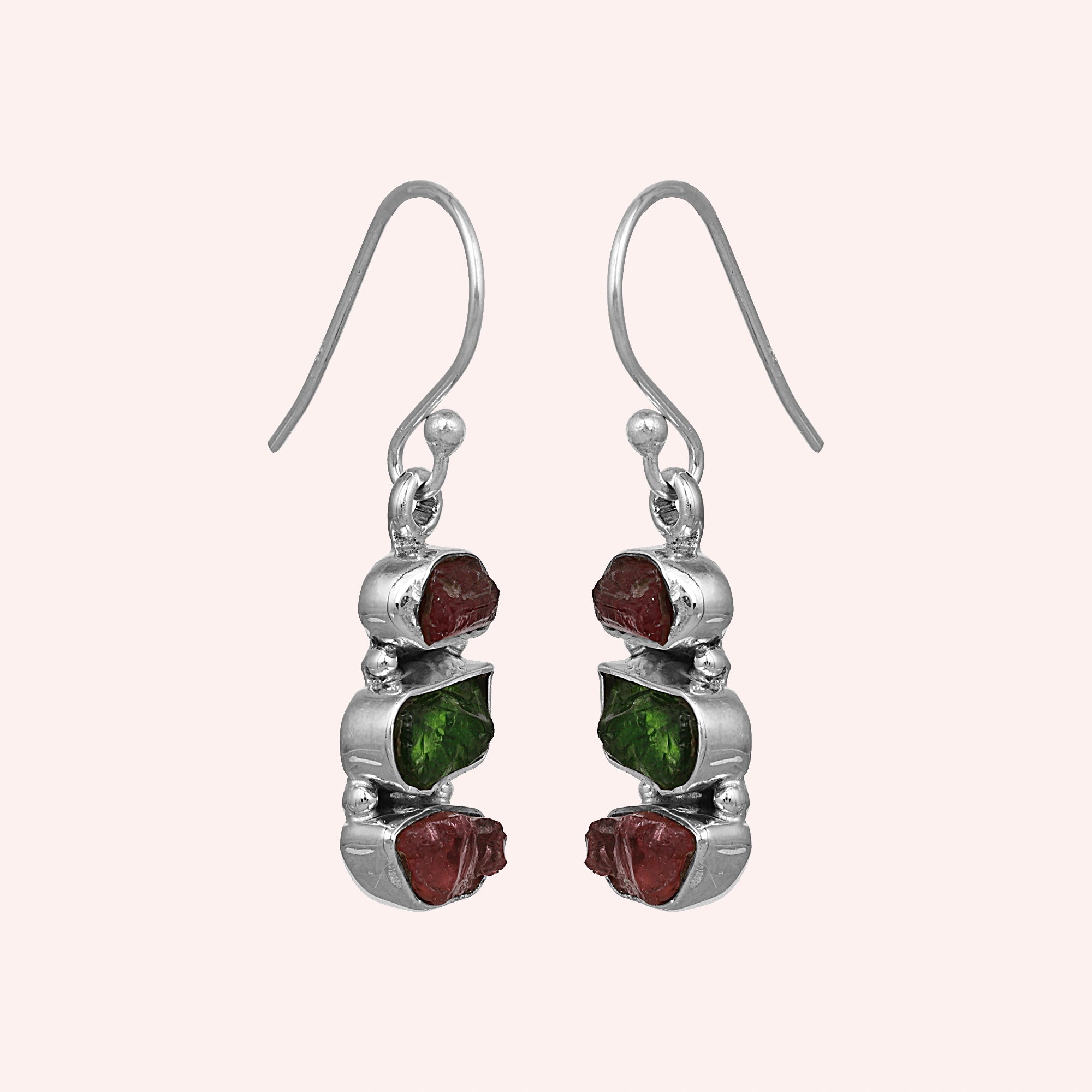 Trending_earrings_in_sterling_silver_with_three_raw_tourmaline_stones_at_slight_angle_view_on_solid_pink_background