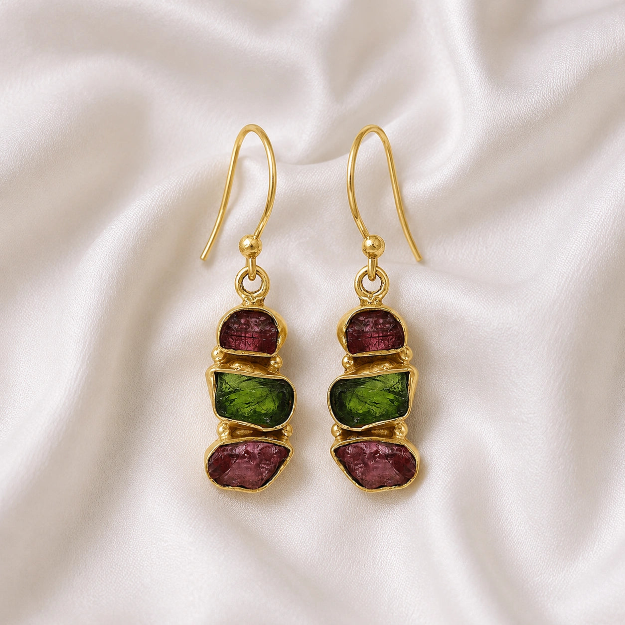 Trending_earrings_in_gold_plated_silver_with_three_raw_tourmaline_stones_at_front_angle_view_on_soft_fabric_background