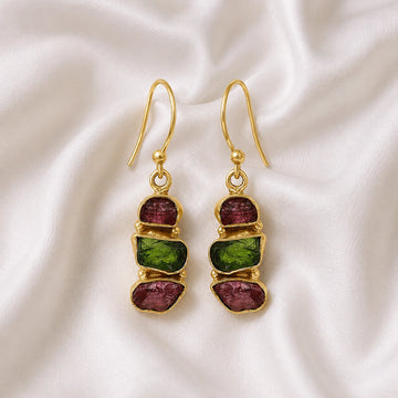 Trending_earrings_in_gold_plated_silver_with_three_raw_tourmaline_stones_at_front_angle_view_on_soft_fabric_background