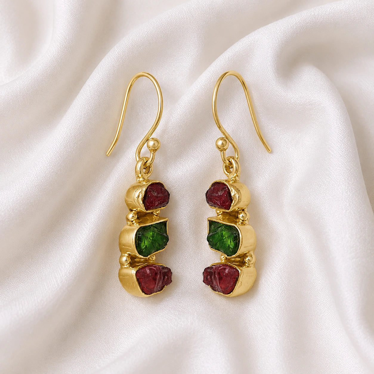 Trending_earrings_in_gold_plated_silver_with_three_raw_tourmaline_stones_at_slight_angle_view_on_soft_fabric_background