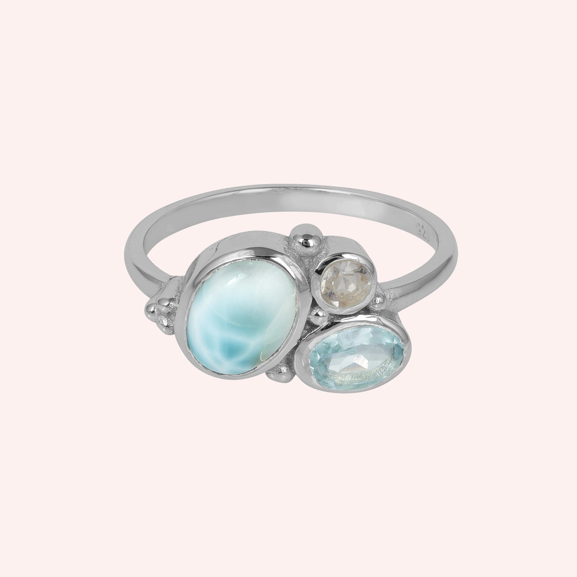 Shot of a beautiful blue stone ring featuring Larimar Blue Topaz and Moonstone on a light pink background viewed straight on