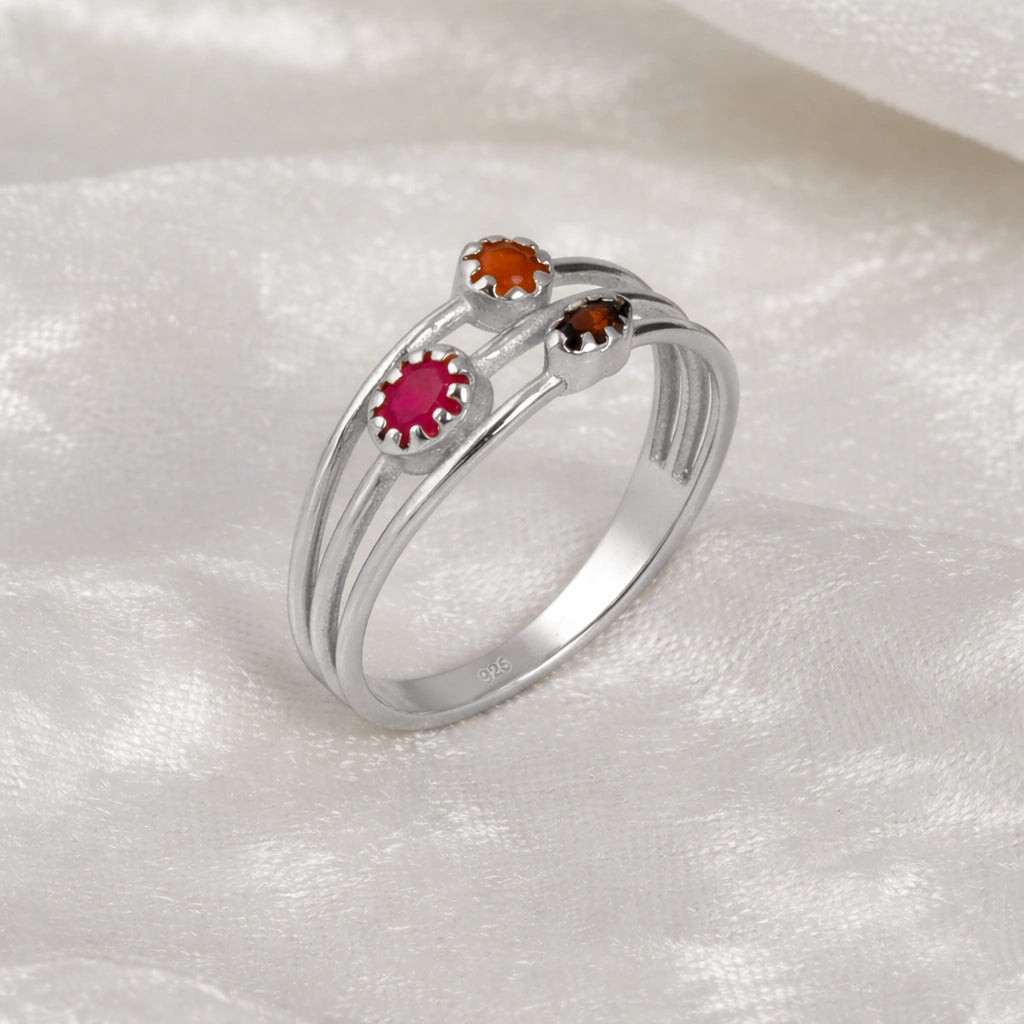 Triple-band-ring-with-ruby-carnelian-and-garnet-gemstones-in-sterling-silver-angled-view-on-white-satin-background