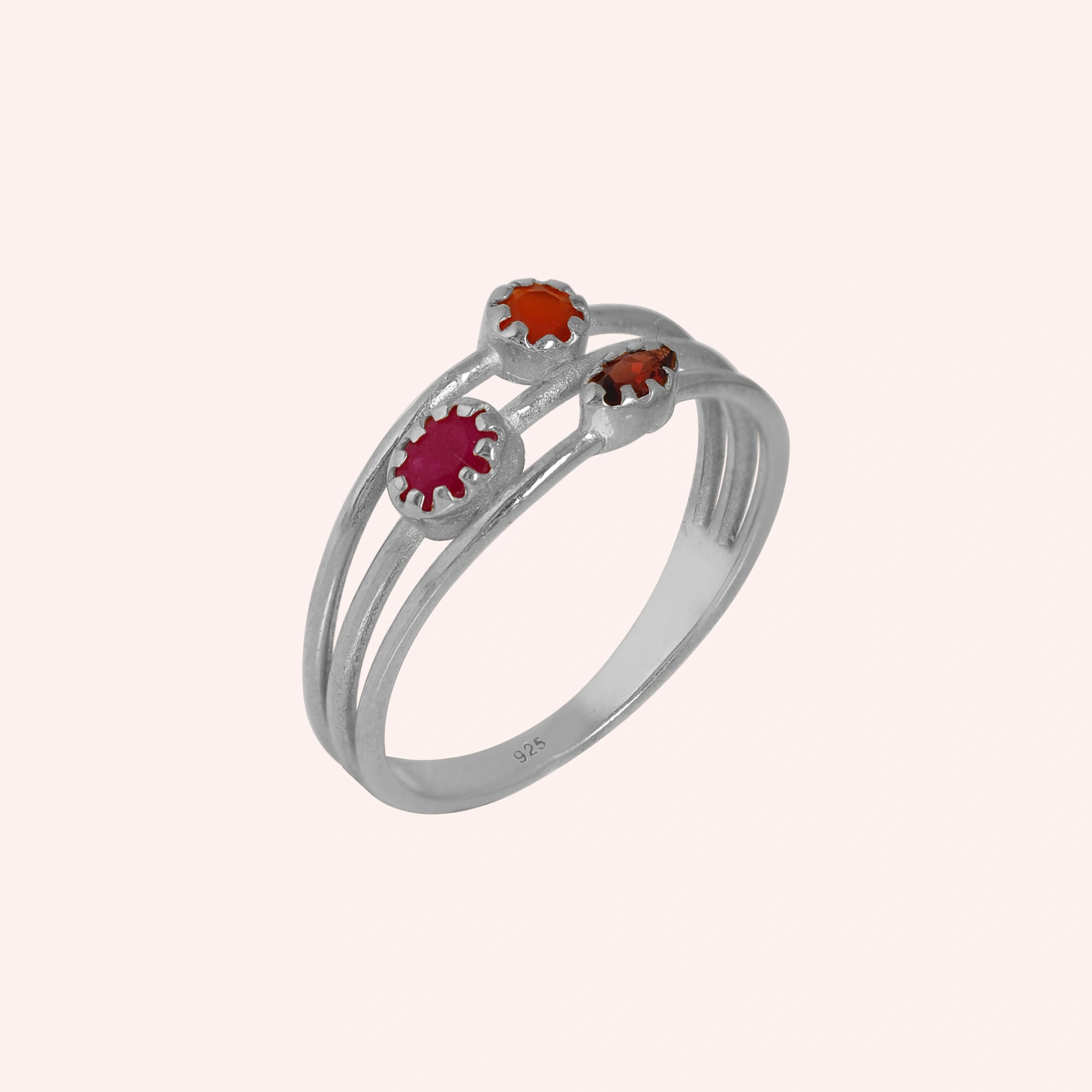 Triple-band-ring-with-ruby-carnelian-and-garnet-gemstones-in-sterling-silver-angled-view-on-soft-pink-background
