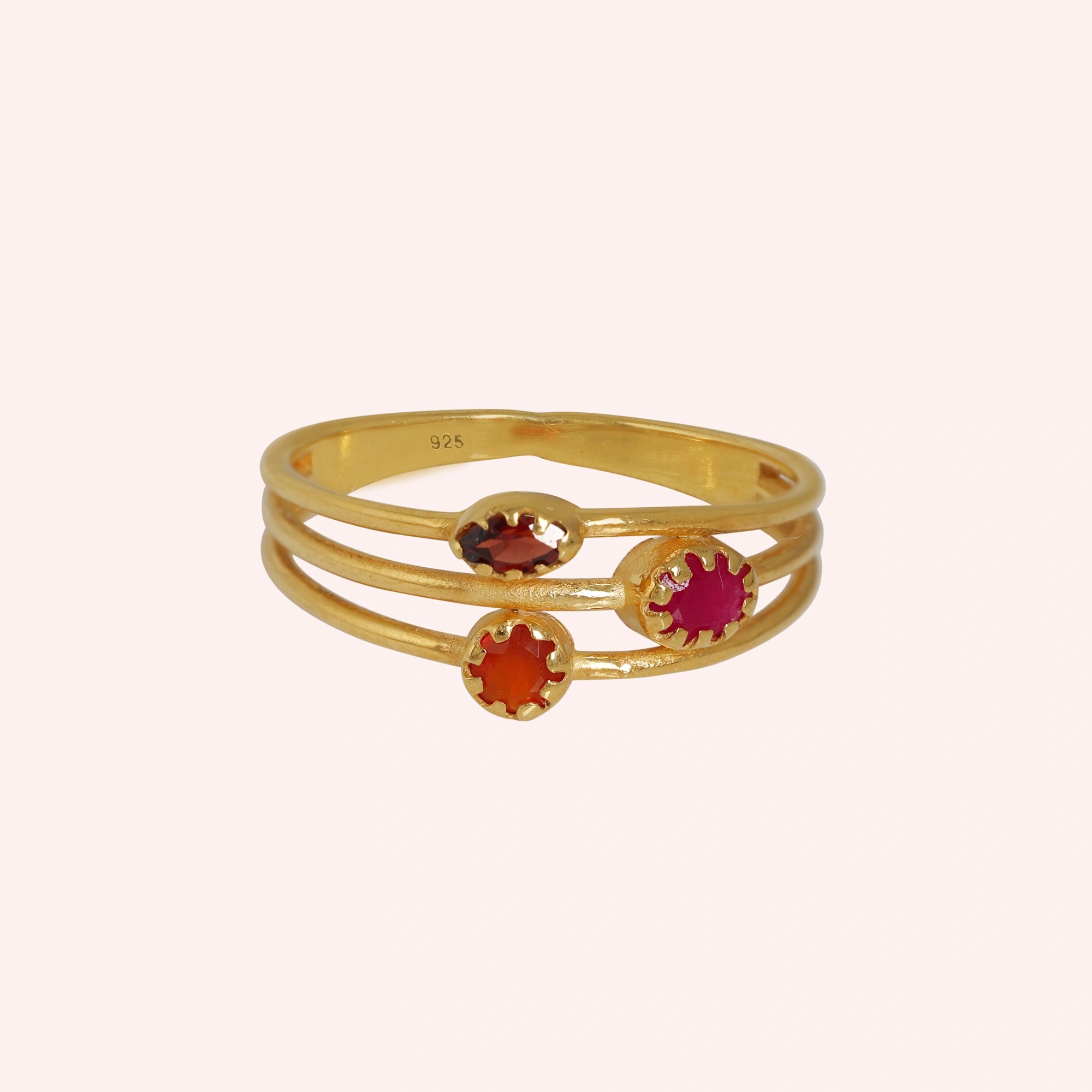 Triple-band-ring-with-ruby-carnelian-garnet-gemstones-in-gold-plated-silver-on-soft-pink-background