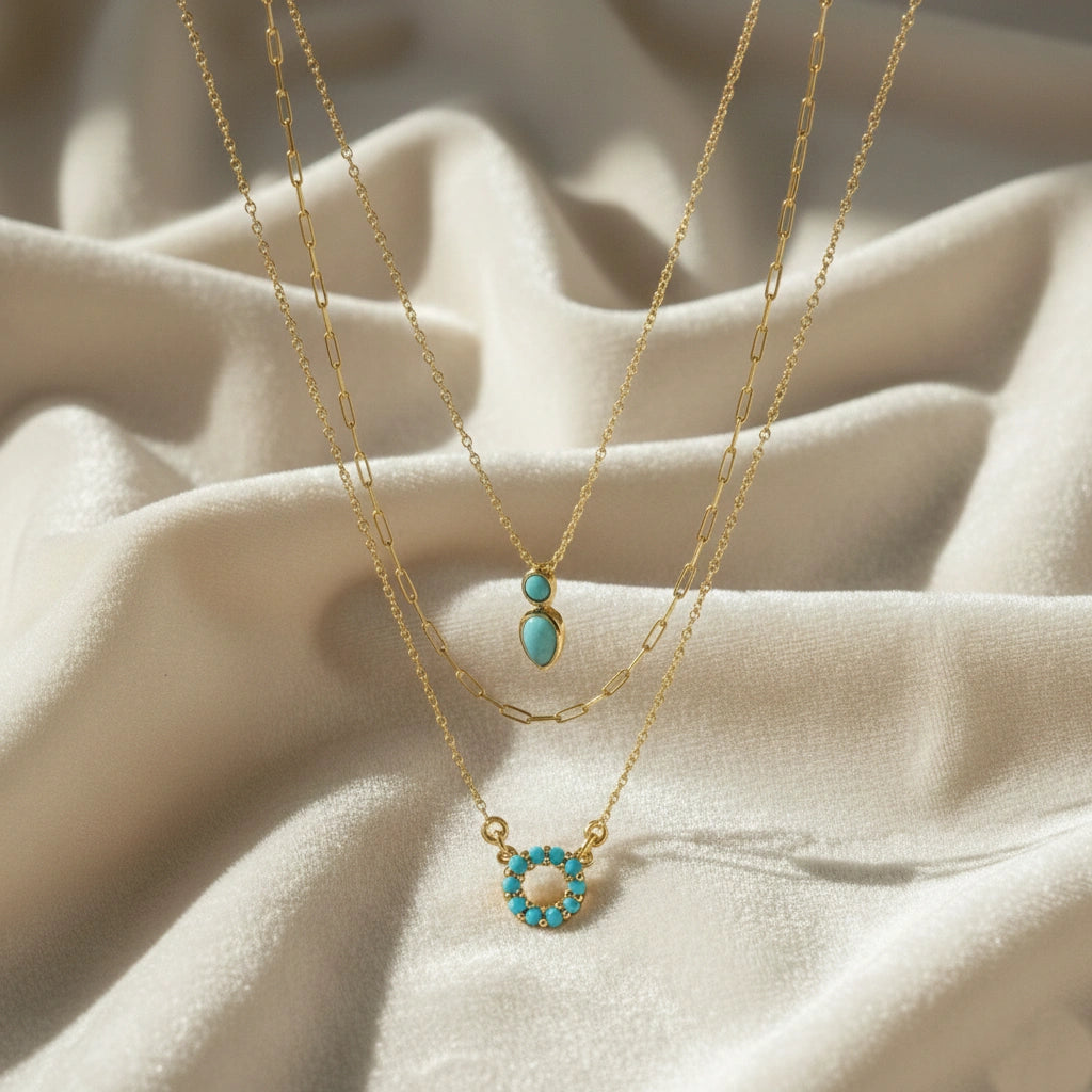 A front angle of gold plated arizona turquoise necklace layered sets and a silver necklace for women a white fabric background