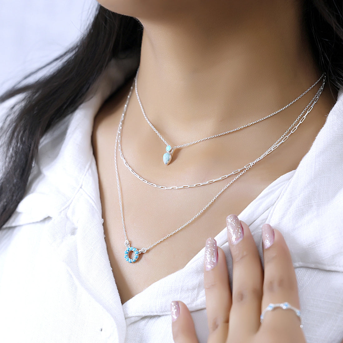 A front angle of gold plated arizona turquoise necklace sets and a silver necklace for women over a white fabric background