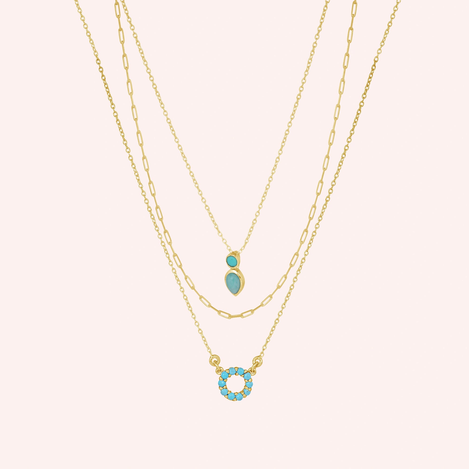 A front angle of gold plated arizona turquoise necklace layered sets and a silver necklace for women over a pink backdrop