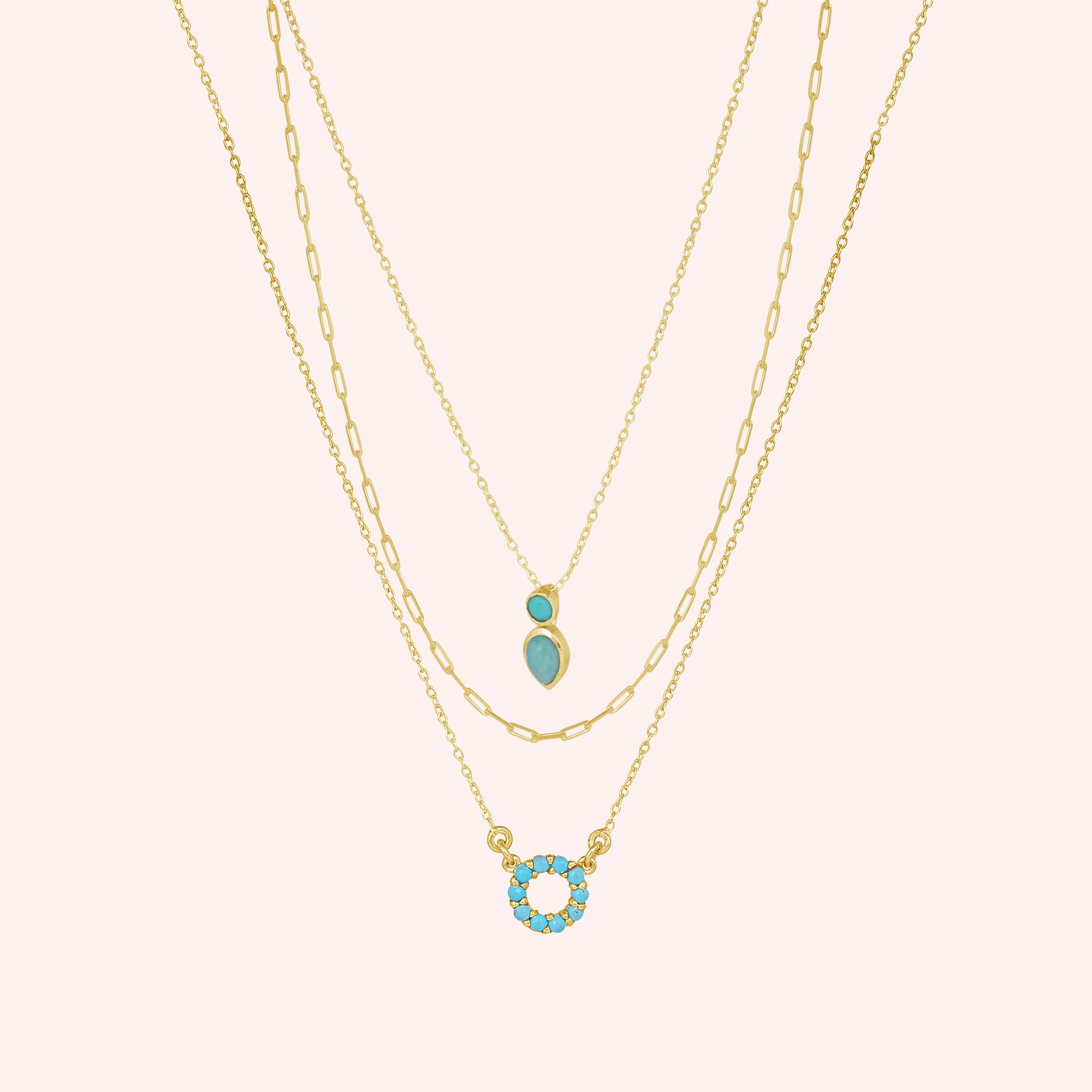 A front angle of gold plated arizona turquoise necklace layered sets and a silver necklace for women over a pink backdrop