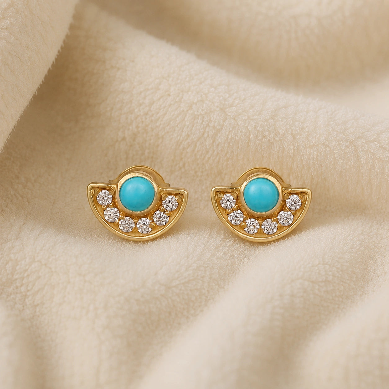 Turquoise_earrings_in_gold_plated_silver_with_turquoise_and_CZ_stones_at_front_angle_view_on_soft_fabric_background