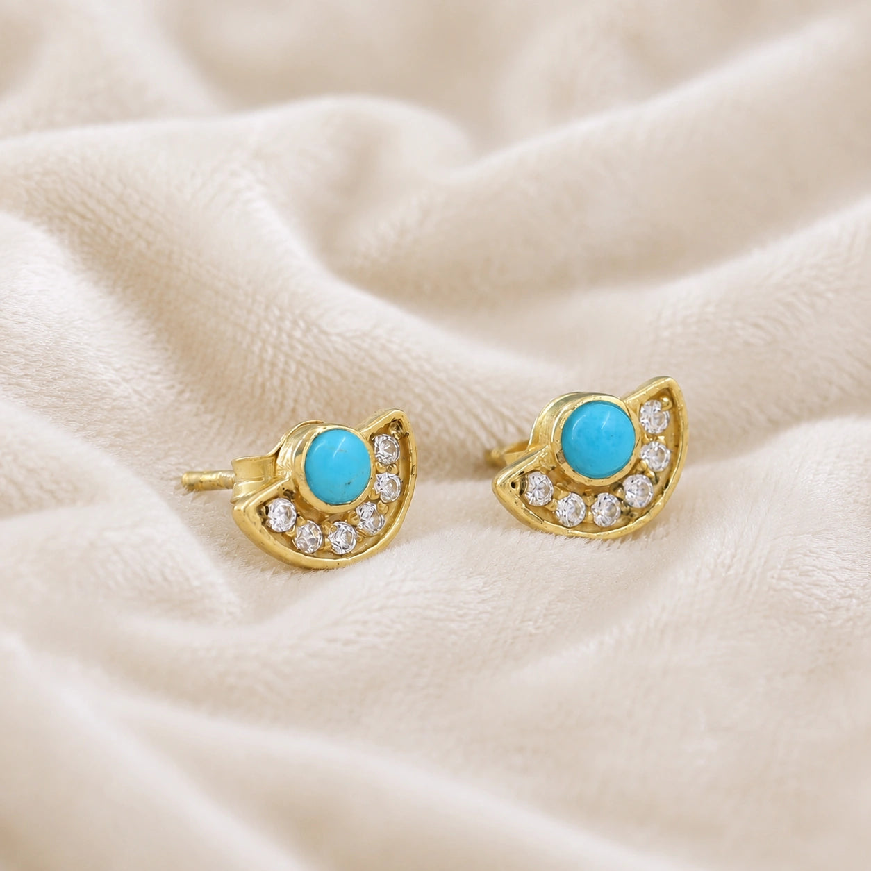 Turquoise_earrings_in_gold_plated_silver_with_turquoise_and_CZ_stones_at_slight_angle_view_on_soft_fabric_background