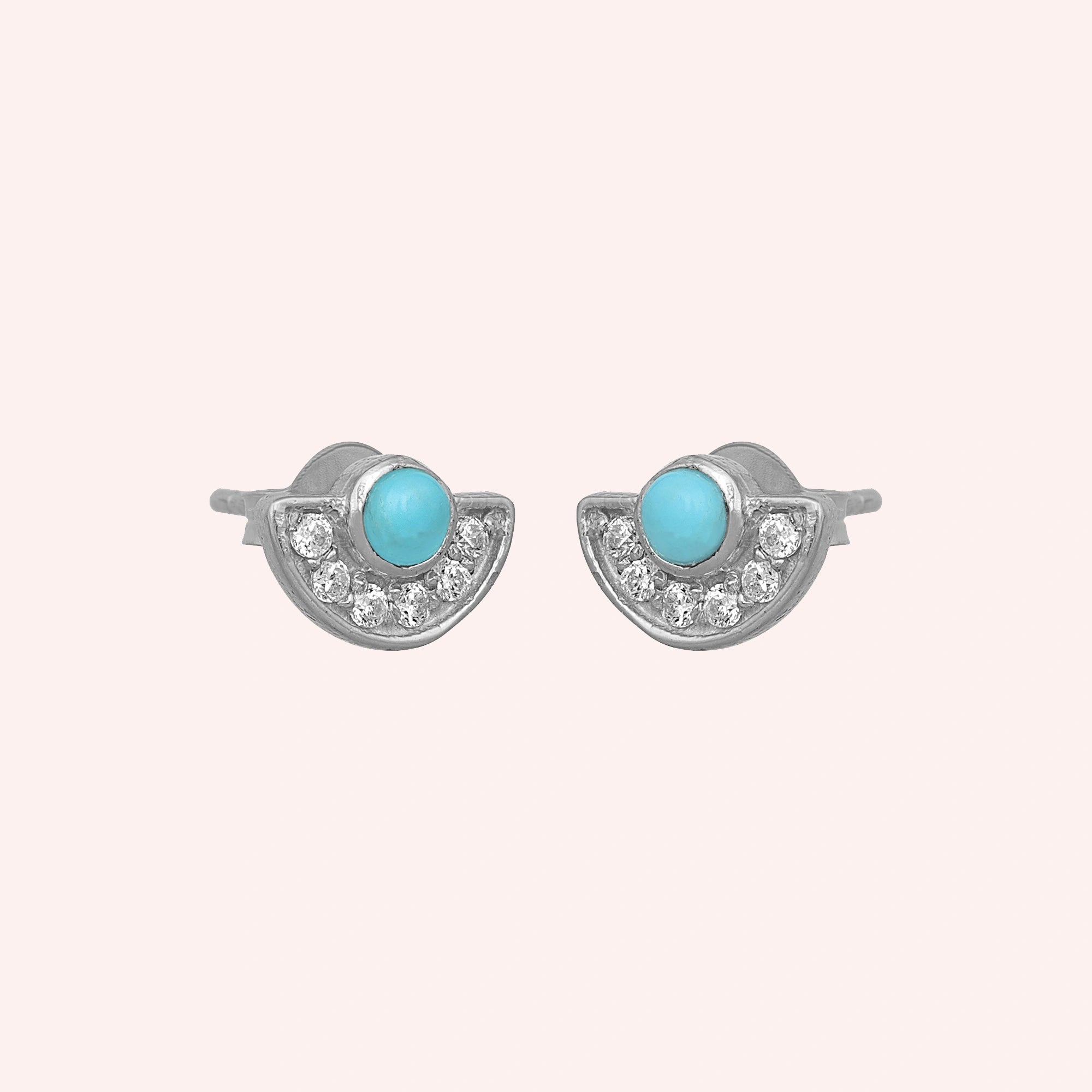 Turquoise_earrings_in_sterling_silver_with_turquoise_and_CZ_stones_at_slight_angle_view_on_solid_pink_background