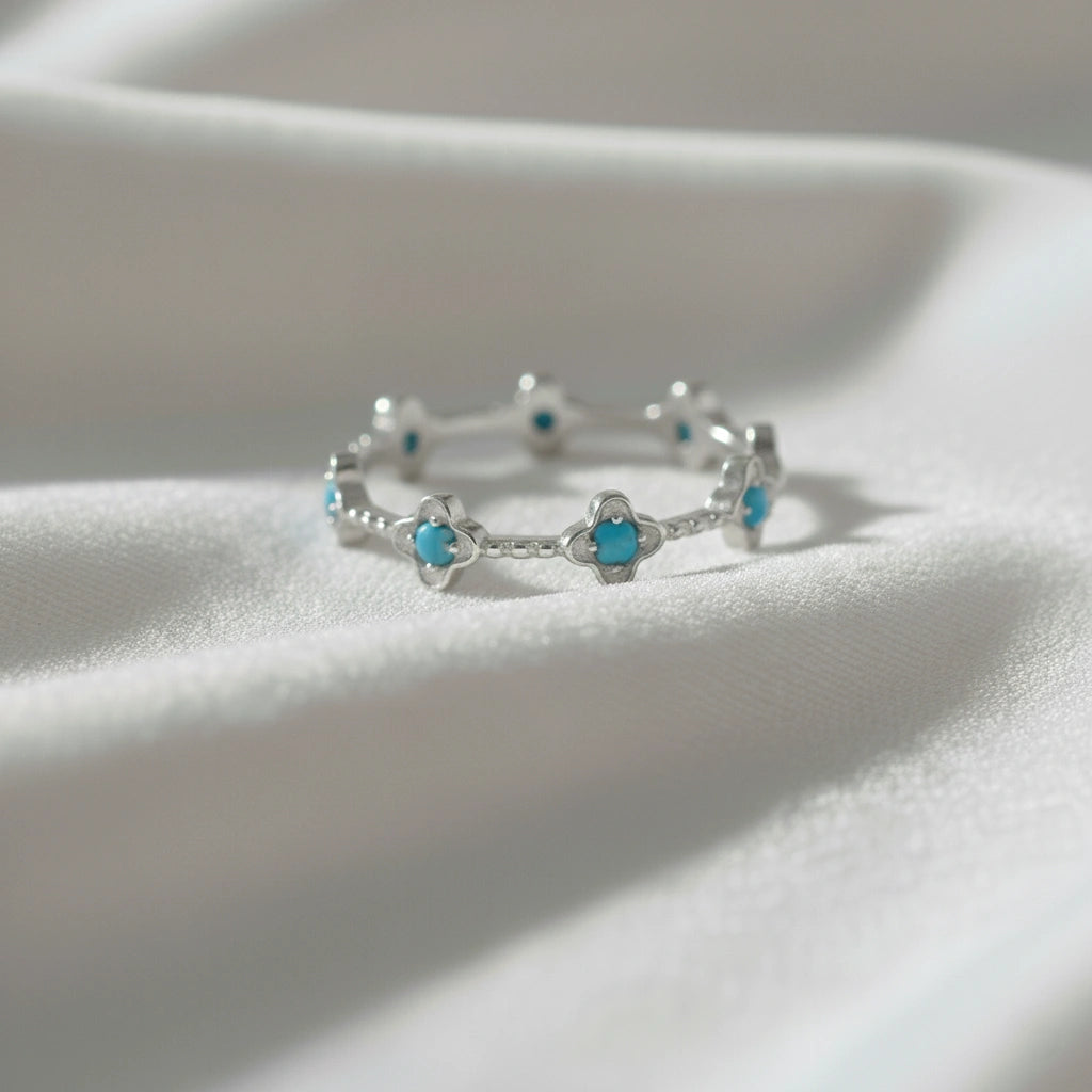 Sterling silver turquoise flower ring with clover shapes on a soft off-white velvet cloth viewed straight on product focus.