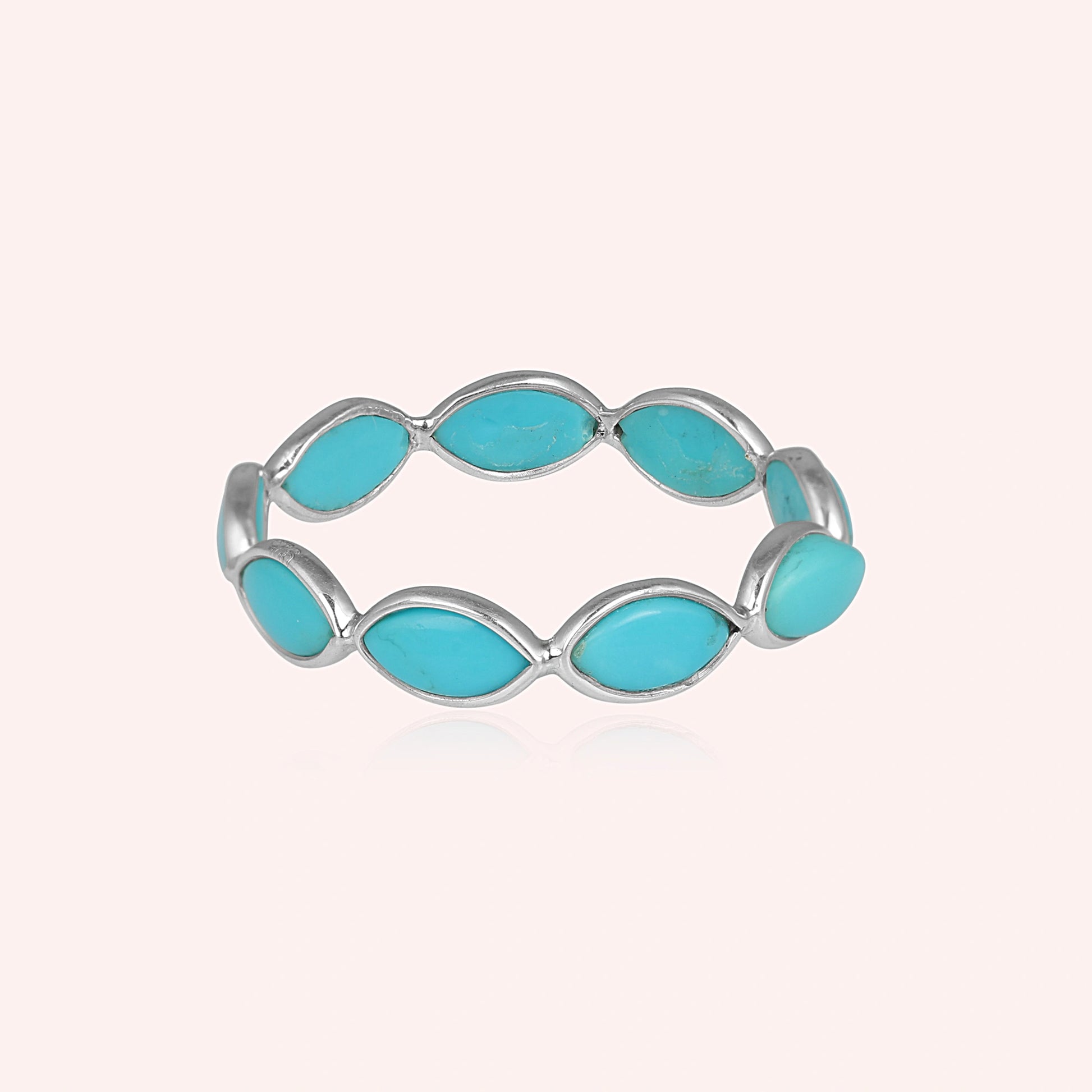 Silver eternity ring with marquise shaped turquoise gemstones set straight on view against a clean light pink background