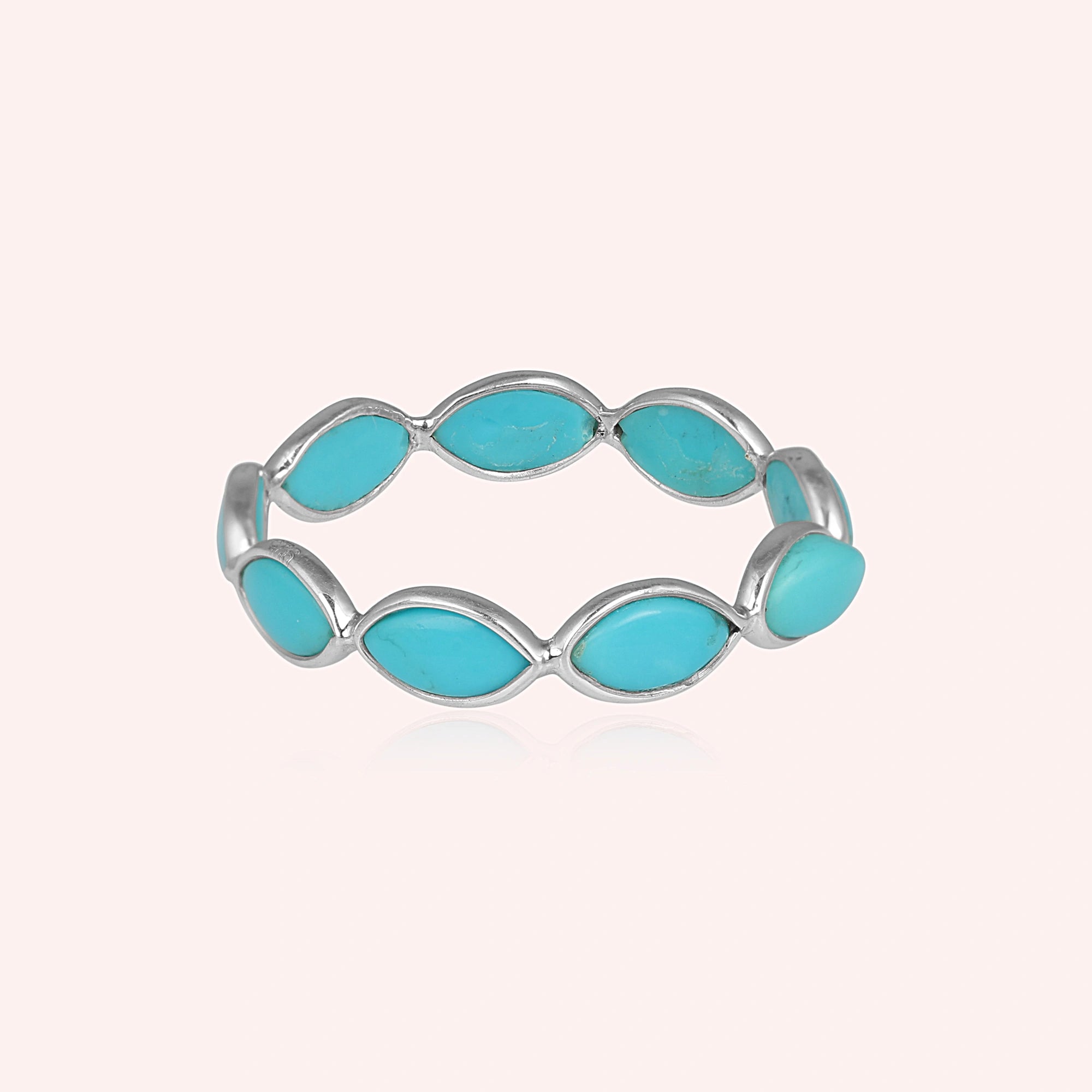 Silver eternity ring with marquise shaped turquoise gemstones set straight on view against a clean light pink background