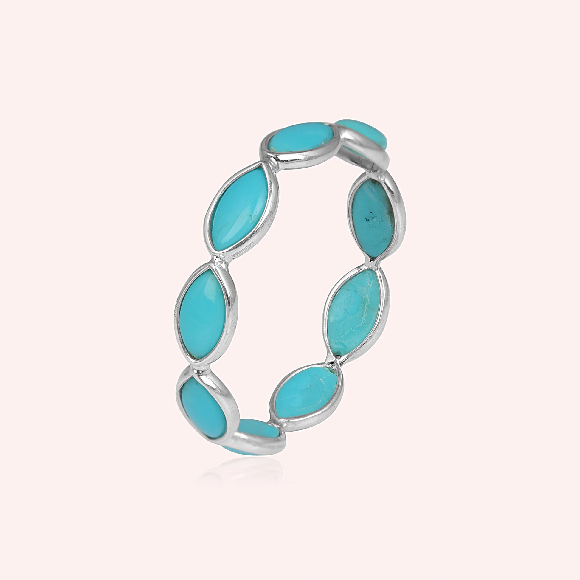 Silver eternity ring with colorful bezel set tourmaline stones elevated angle view against a minimal light pink background