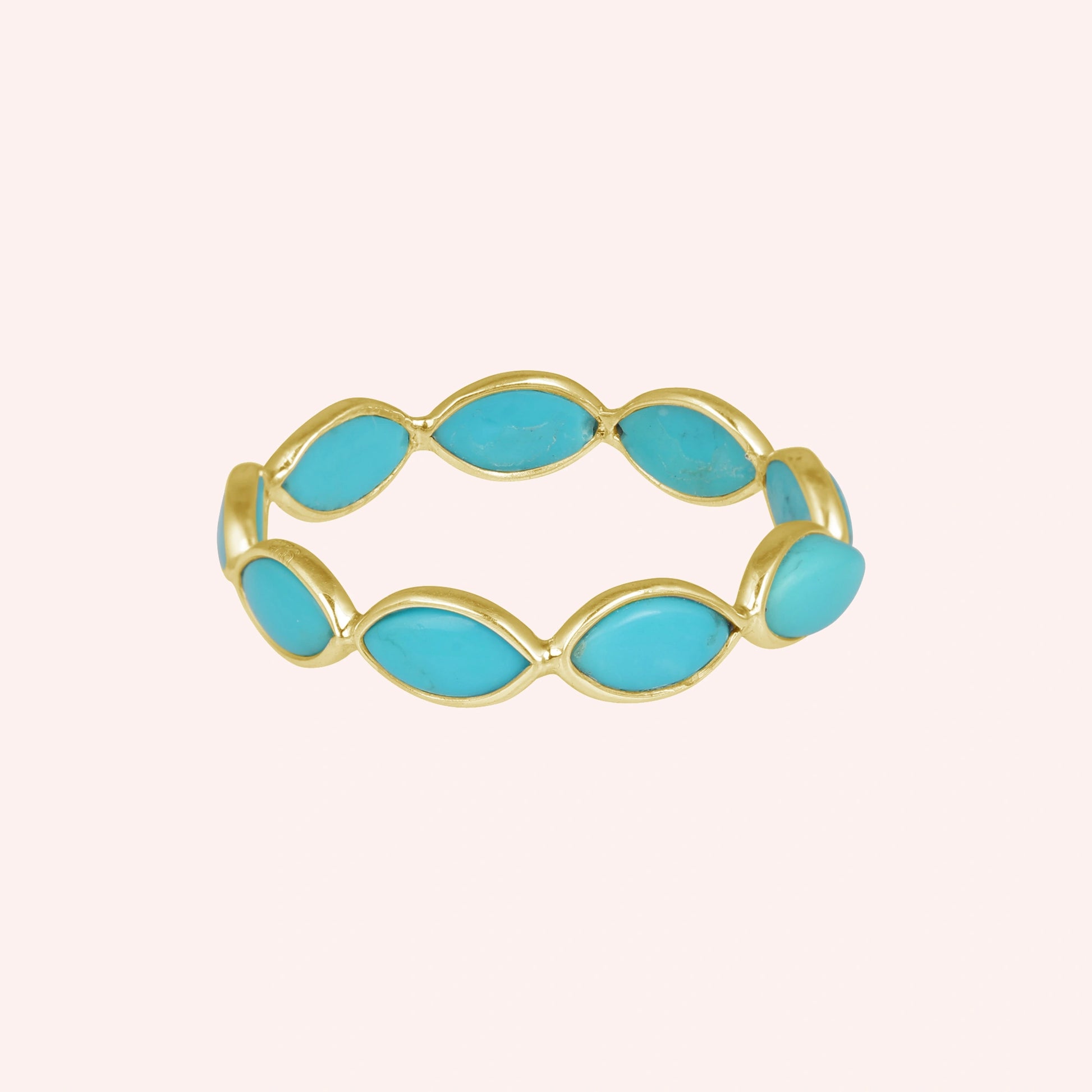 Gold plated silver eternity ring with marquise cut turquoise gemstones set straight on view against light pink background
